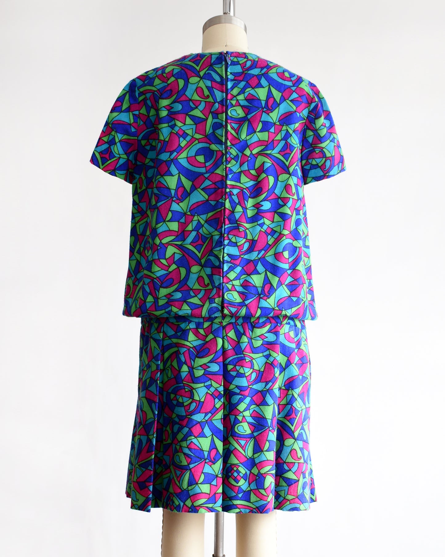 back view of a vintage 1960s psychedelic patterned dress on a mannequin against a white background