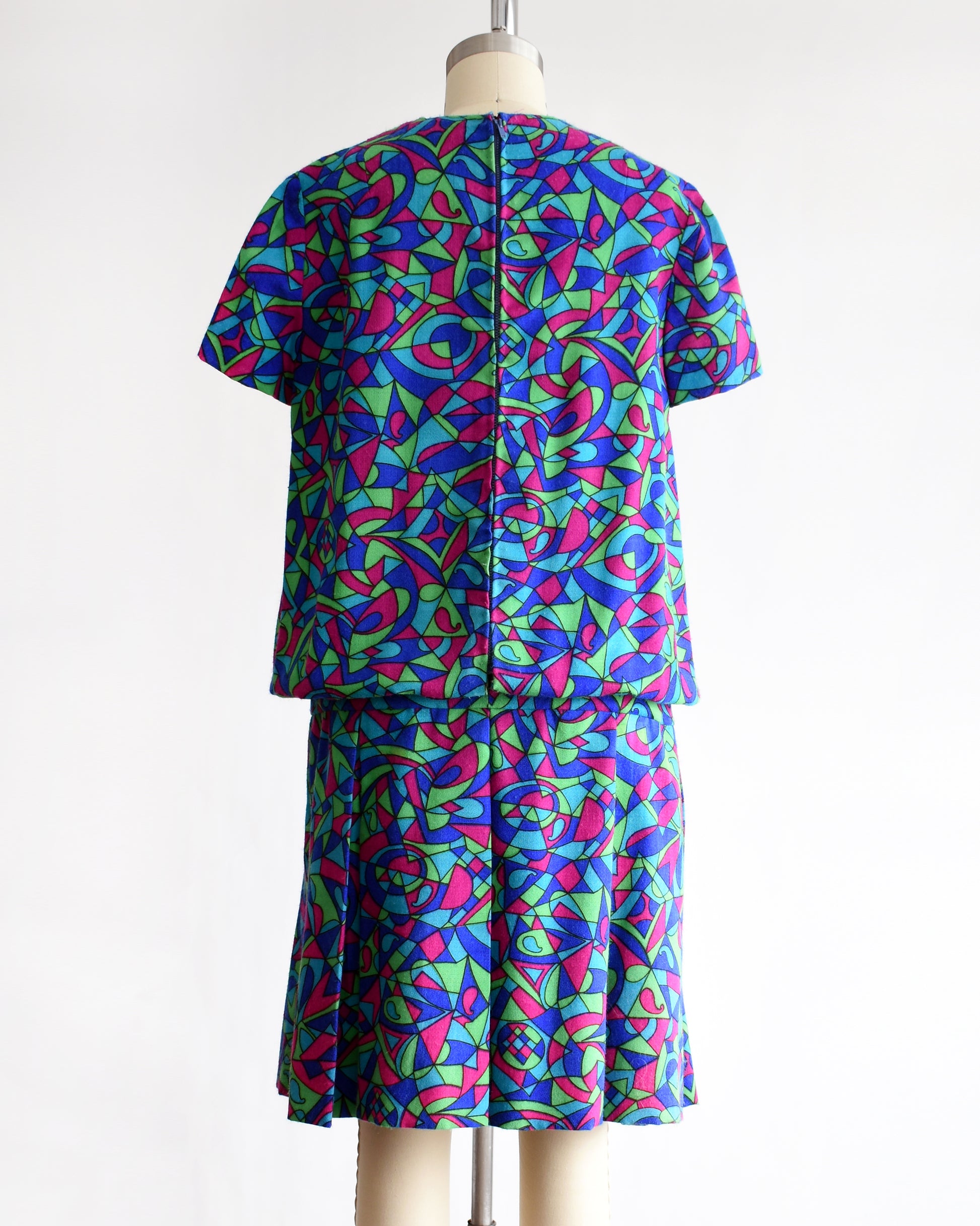back view of a vintage 1960s psychedelic patterned dress on a mannequin against a white background
