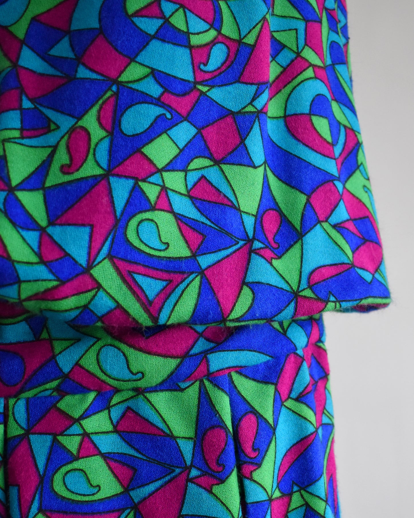 close up of the drop waist on a vintage 1960s psychedelic patterned dress on a mannequin against a white background