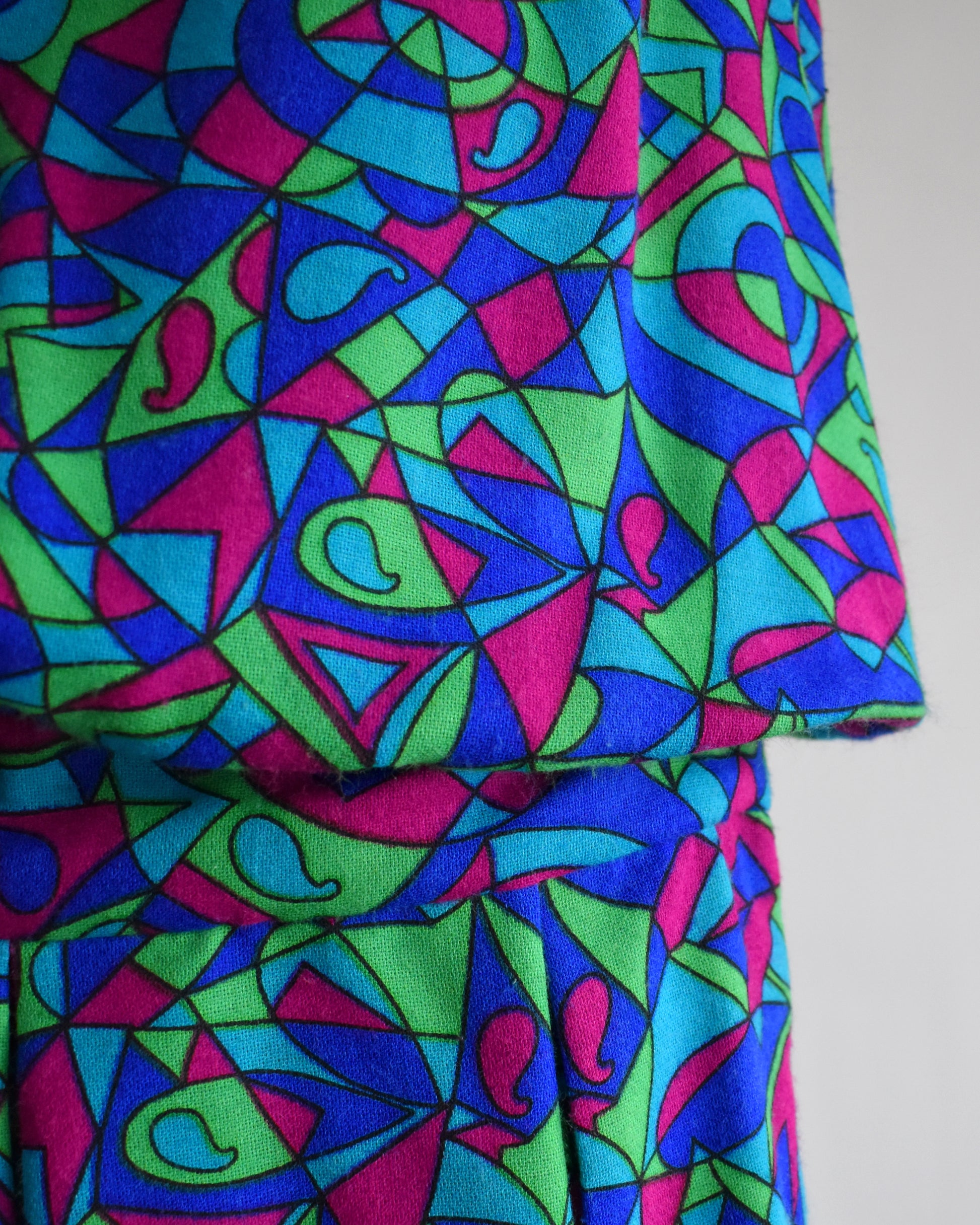 close up of the drop waist on a vintage 1960s psychedelic patterned dress on a mannequin against a white background
