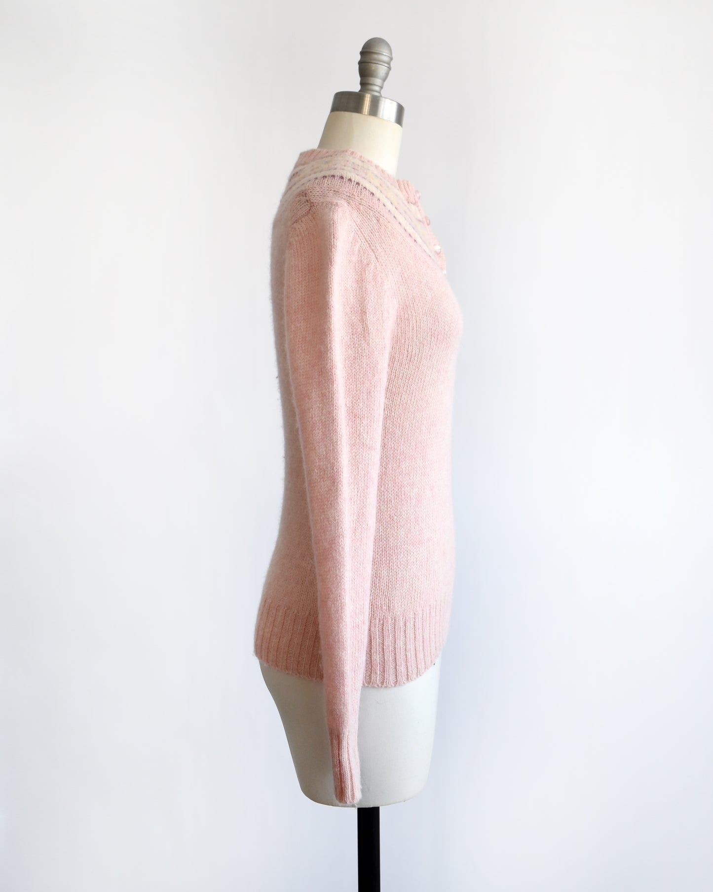 side view of a vintage 1980s pink sweater on a mannequin against a white background