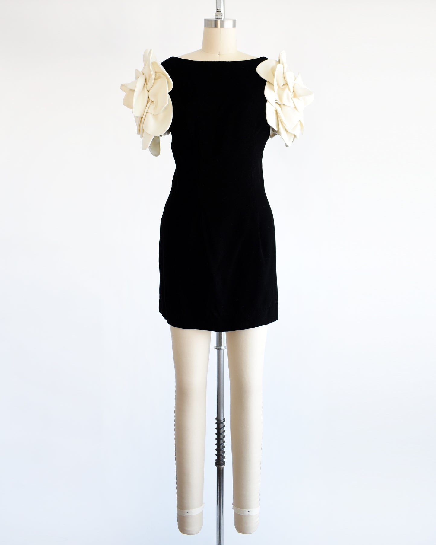 a vintage 1980s Victor Costa black dress with white floral sleeves on a mannequin against a white background