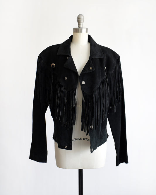 a vintage 1990s black fringed jacket on a mannequin against a white background