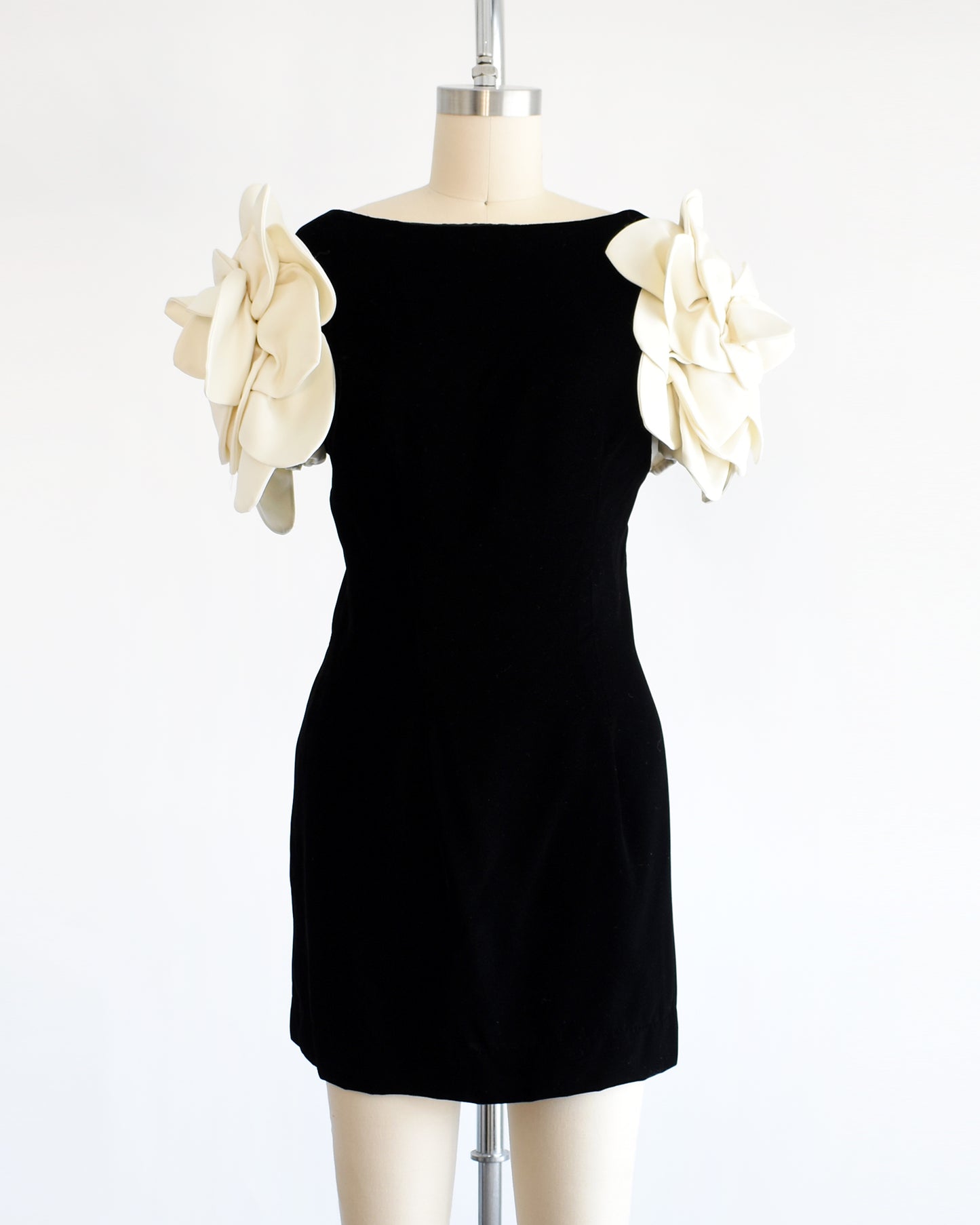 a vintage 1980s Victor Costa black dress with white floral sleeves on a mannequin against a white background