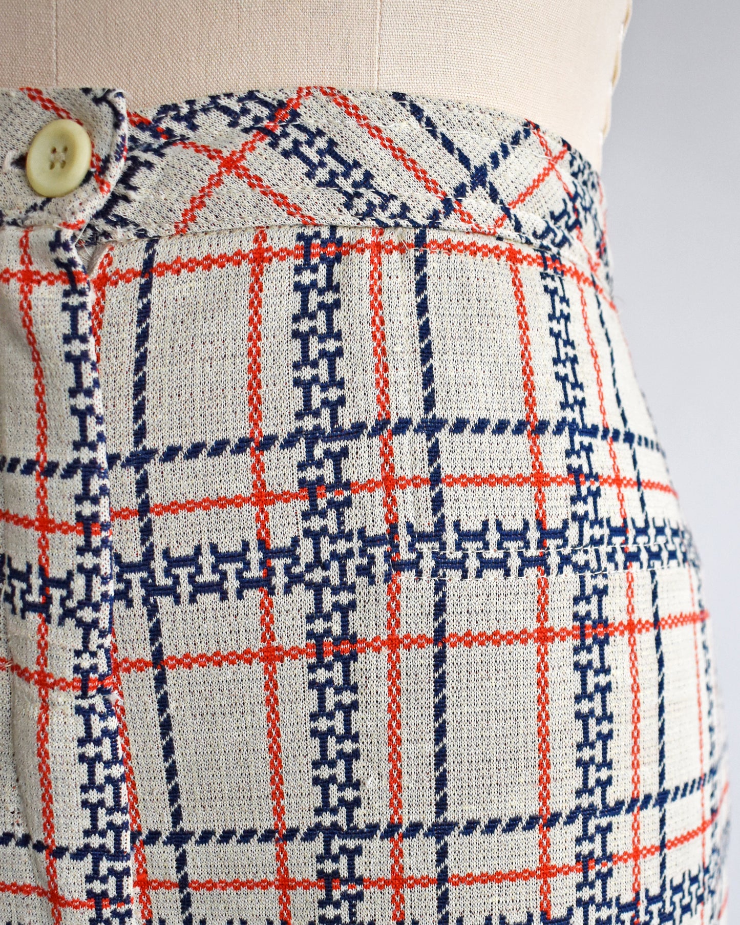 close up of the waist on vintage 1970s plaid pants on a mannequin against a white background