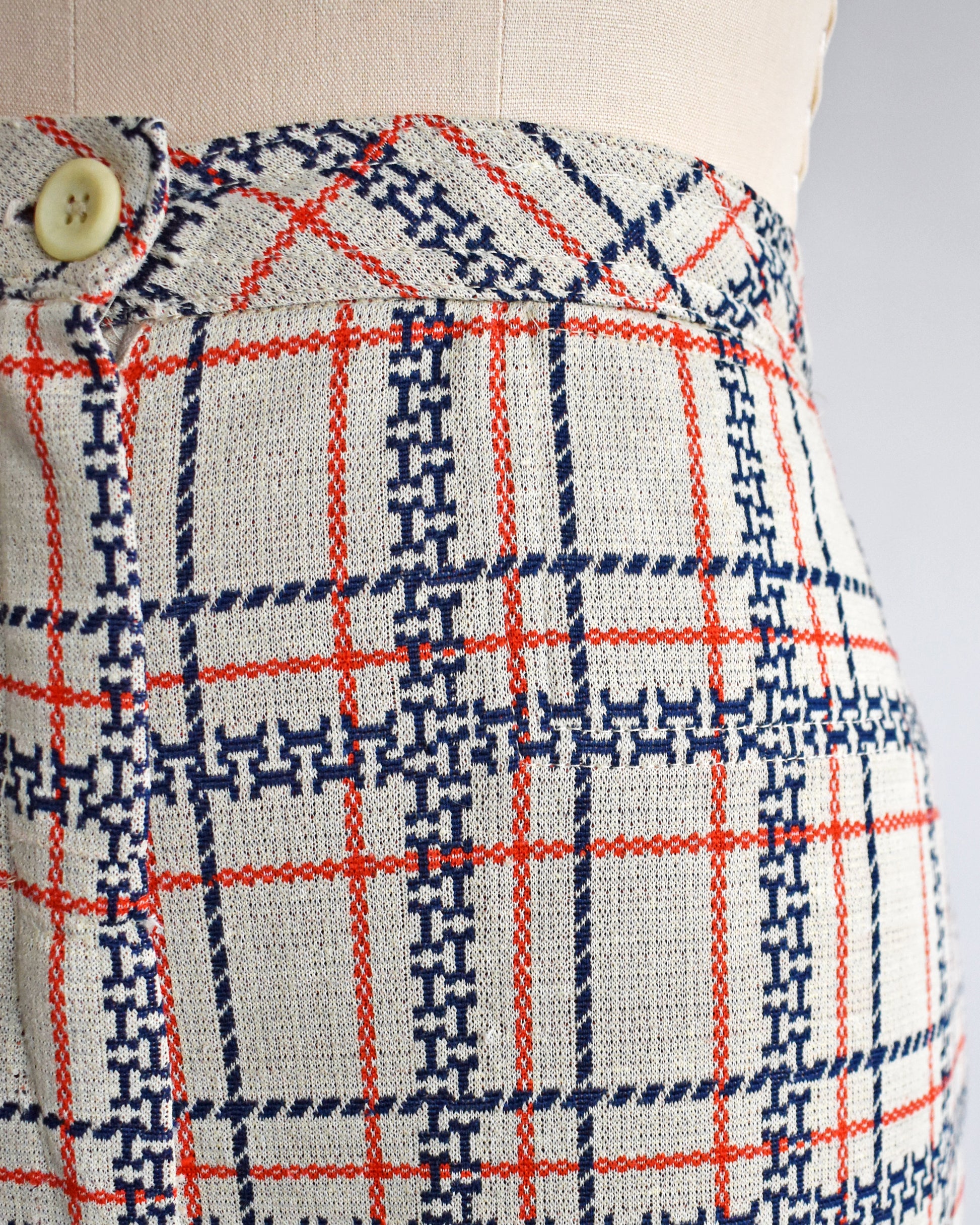 close up of the waist on vintage 1970s plaid pants on a mannequin against a white background