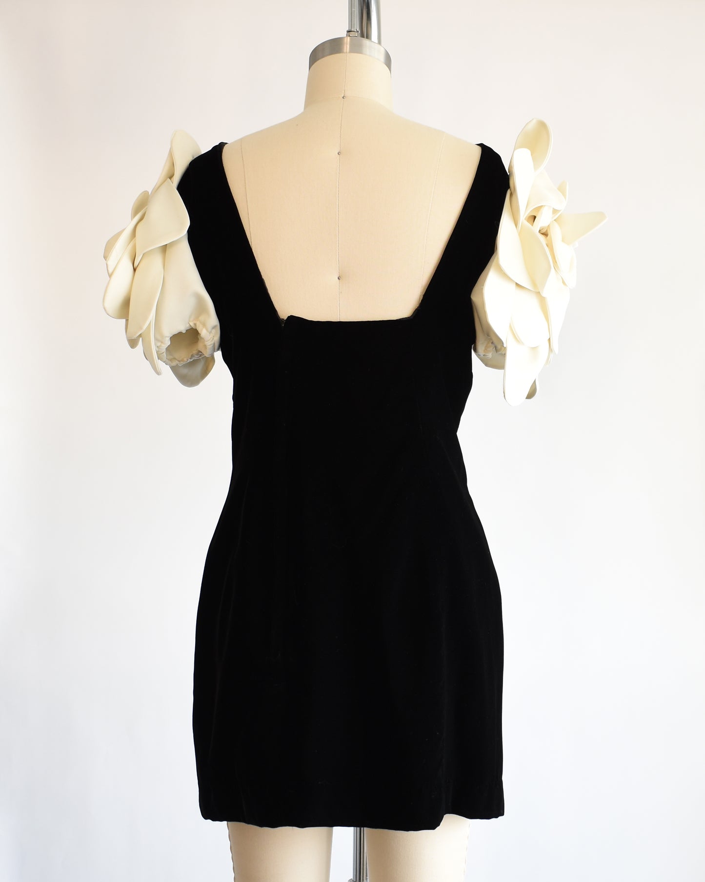 back view of a vintage 1980s Victor Costa black dress with white floral sleeves on a mannequin against a white background
