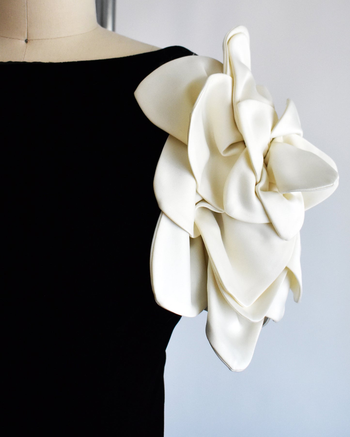 close up of the floral sleeve on a vintage 1980s Victor Costa black dress with white floral sleeves on a mannequin against a white background