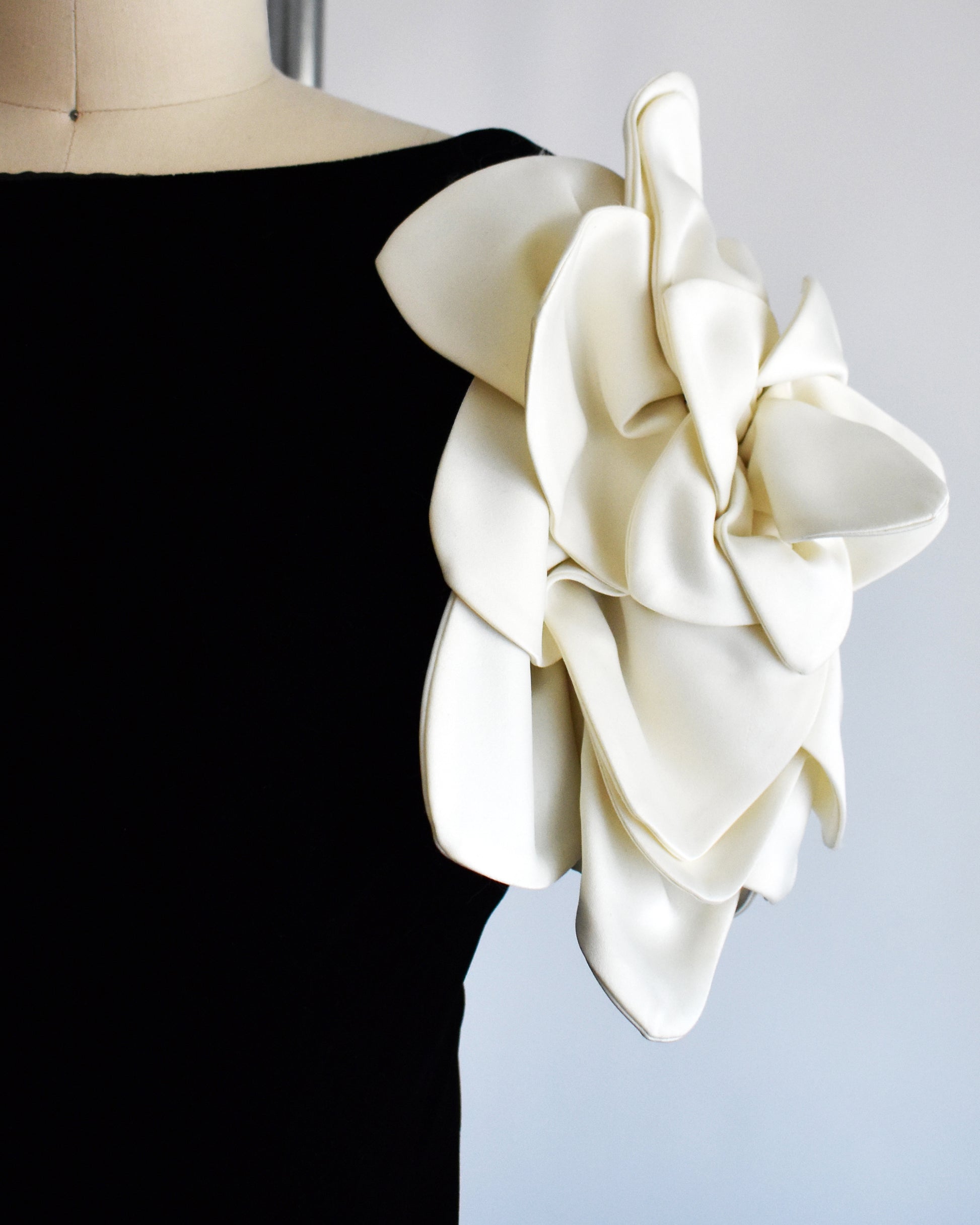 close up of the floral sleeve on a vintage 1980s Victor Costa black dress with white floral sleeves on a mannequin against a white background
