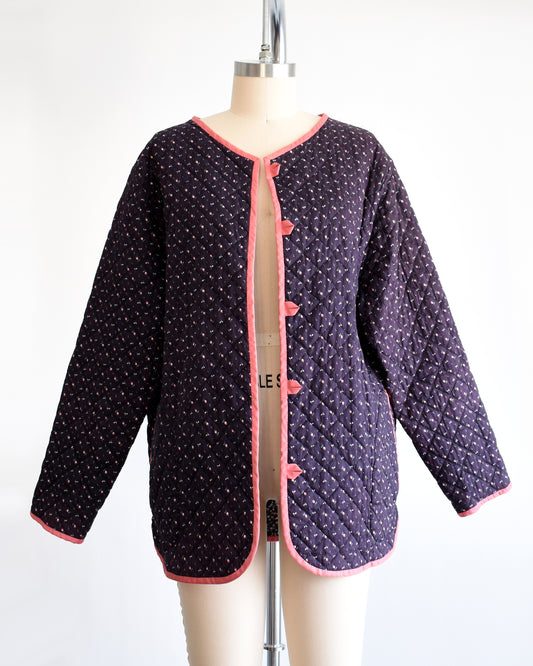 a vintage 1970s/1980s purple floral quilted jacket with pink trim on a mannequin on a dress form