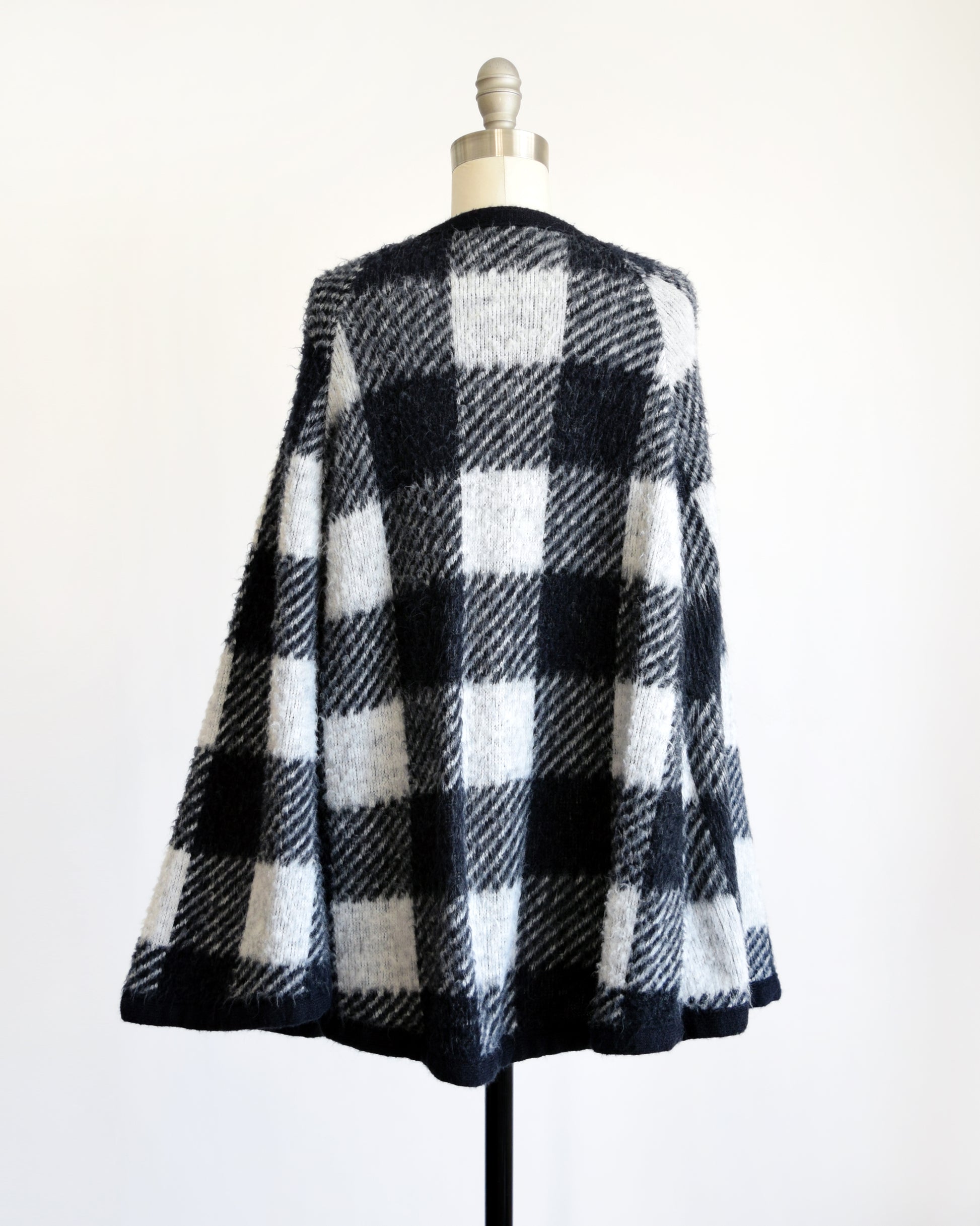 Back view of a vintage 1970s black and white plaid poncho 