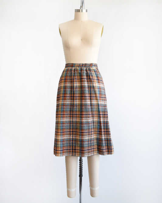 a vintage 1970s brown and blue plaid skirt on a dress form against a white background