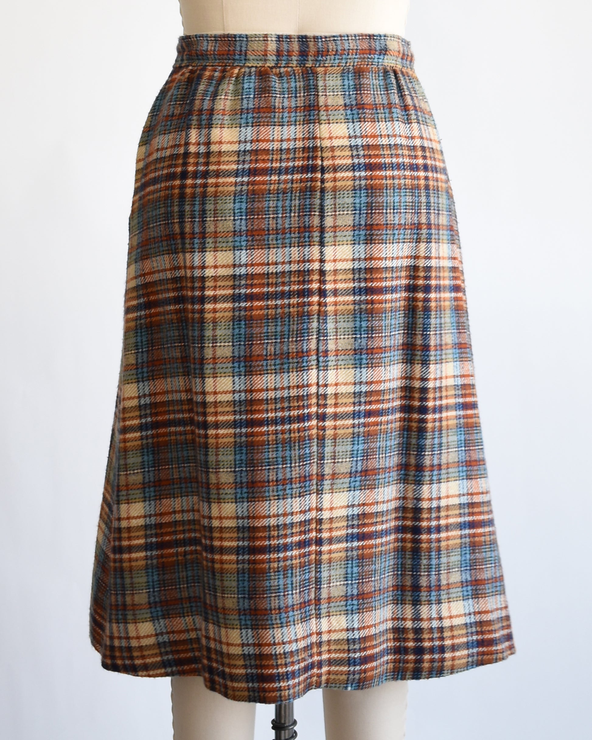 back view of a vintage 1970s brown and blue plaid skirt on a dress form against a white background