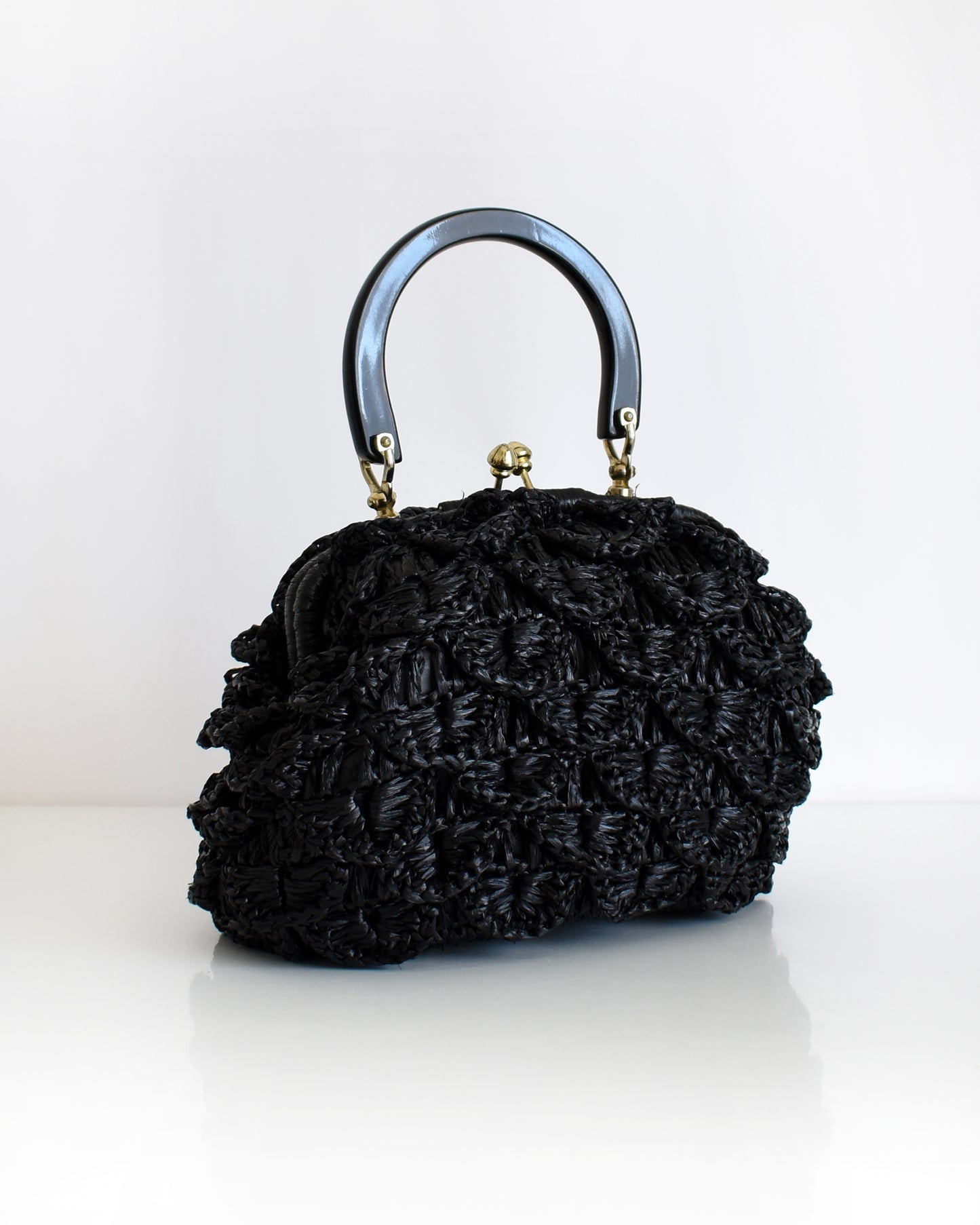 a vintage black woven raffia handbag with a handle on a white background