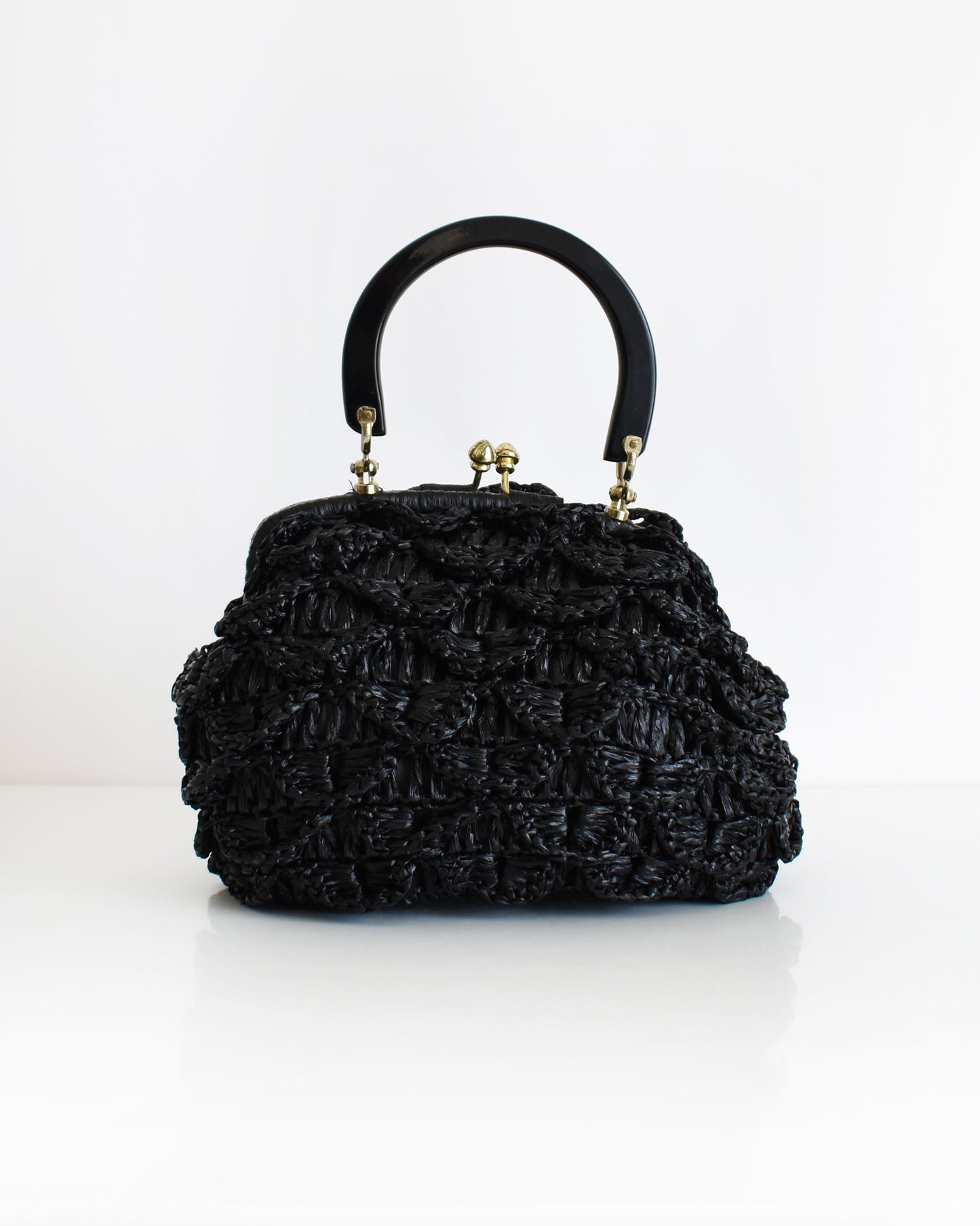 a vintage black woven raffia handbag with a handle on a white background