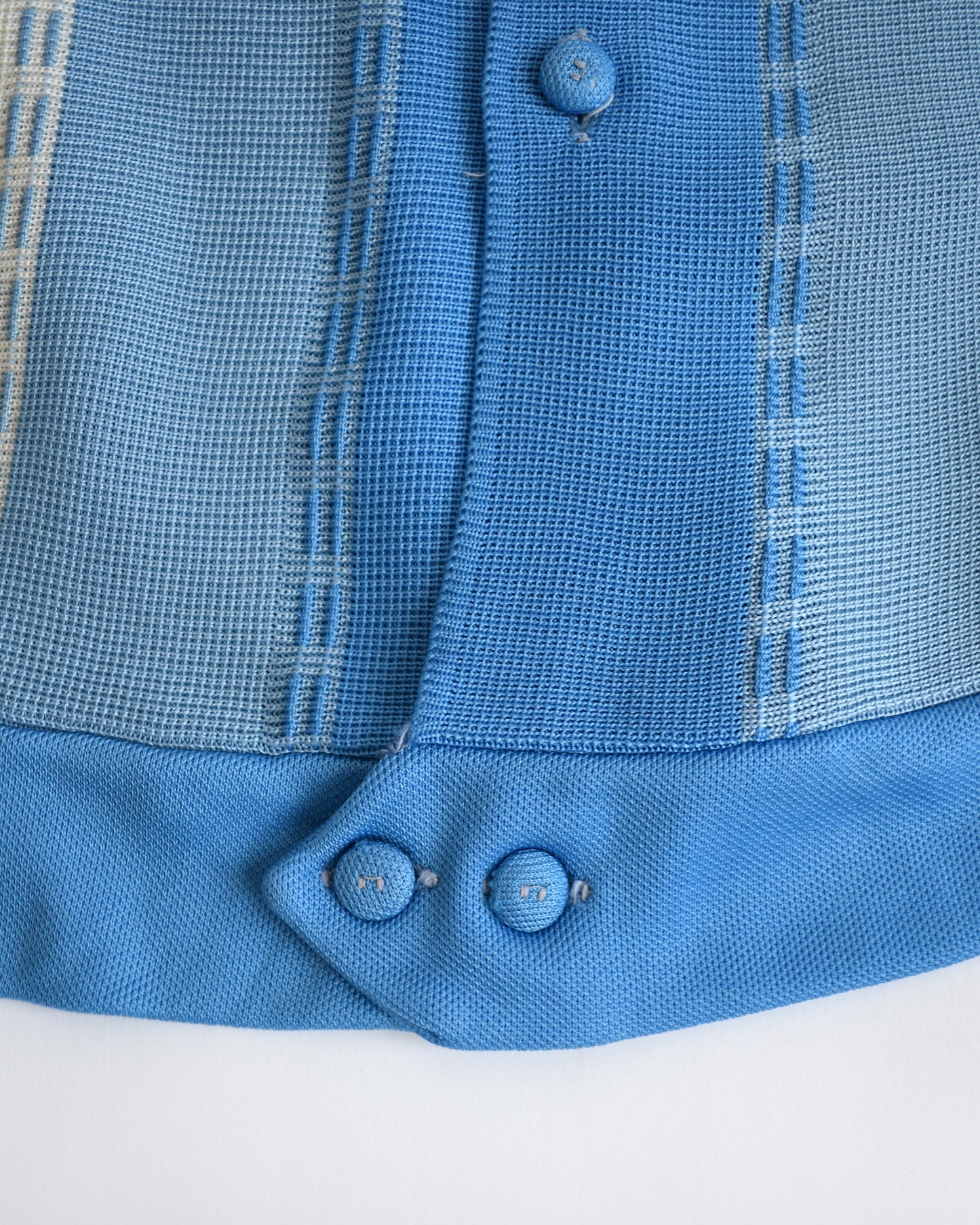 Close-up of a blue textured fabric with buttons on a white background
