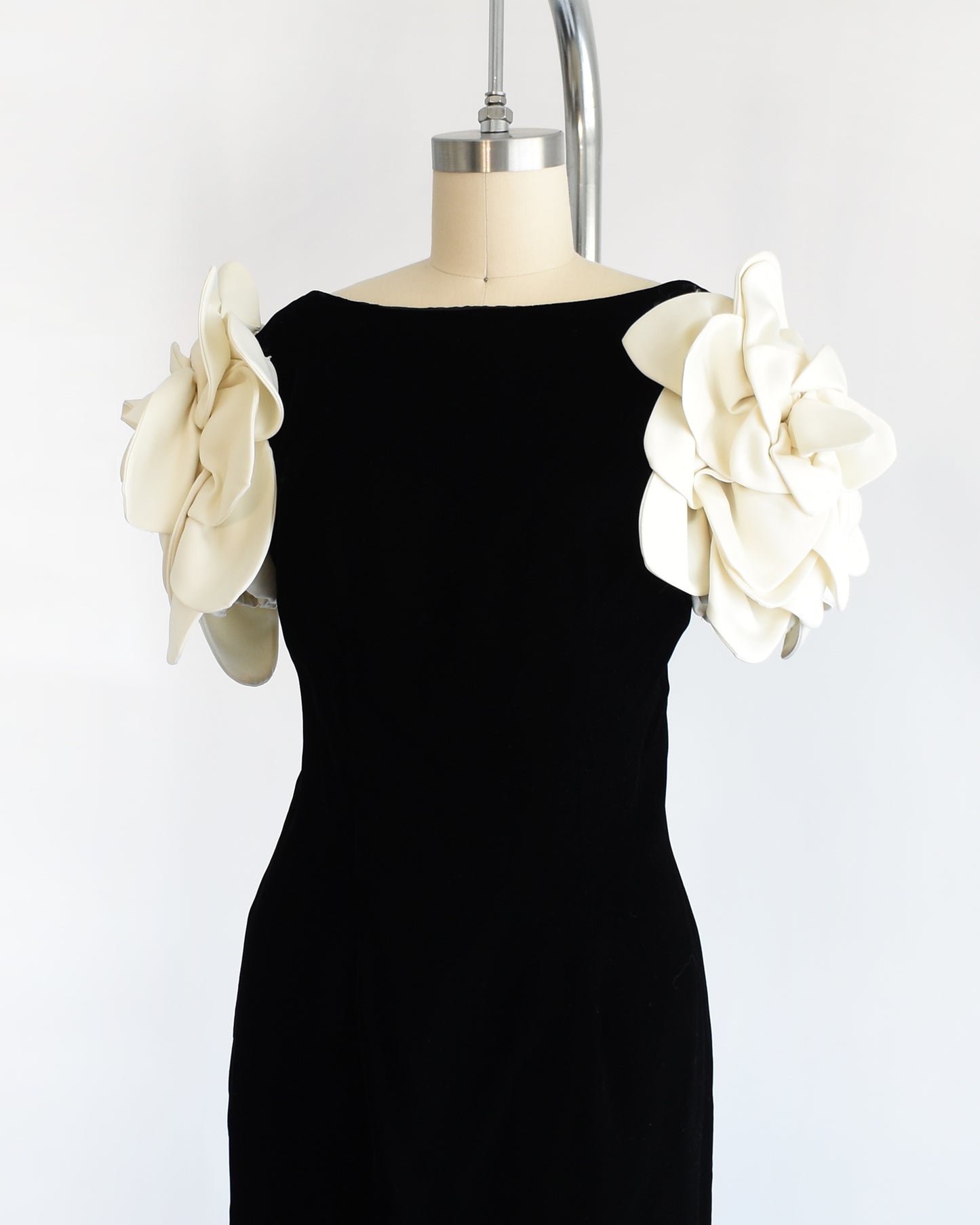 side front view of a vintage 1980s Victor Costa black dress with white floral sleeves on a mannequin against a white background