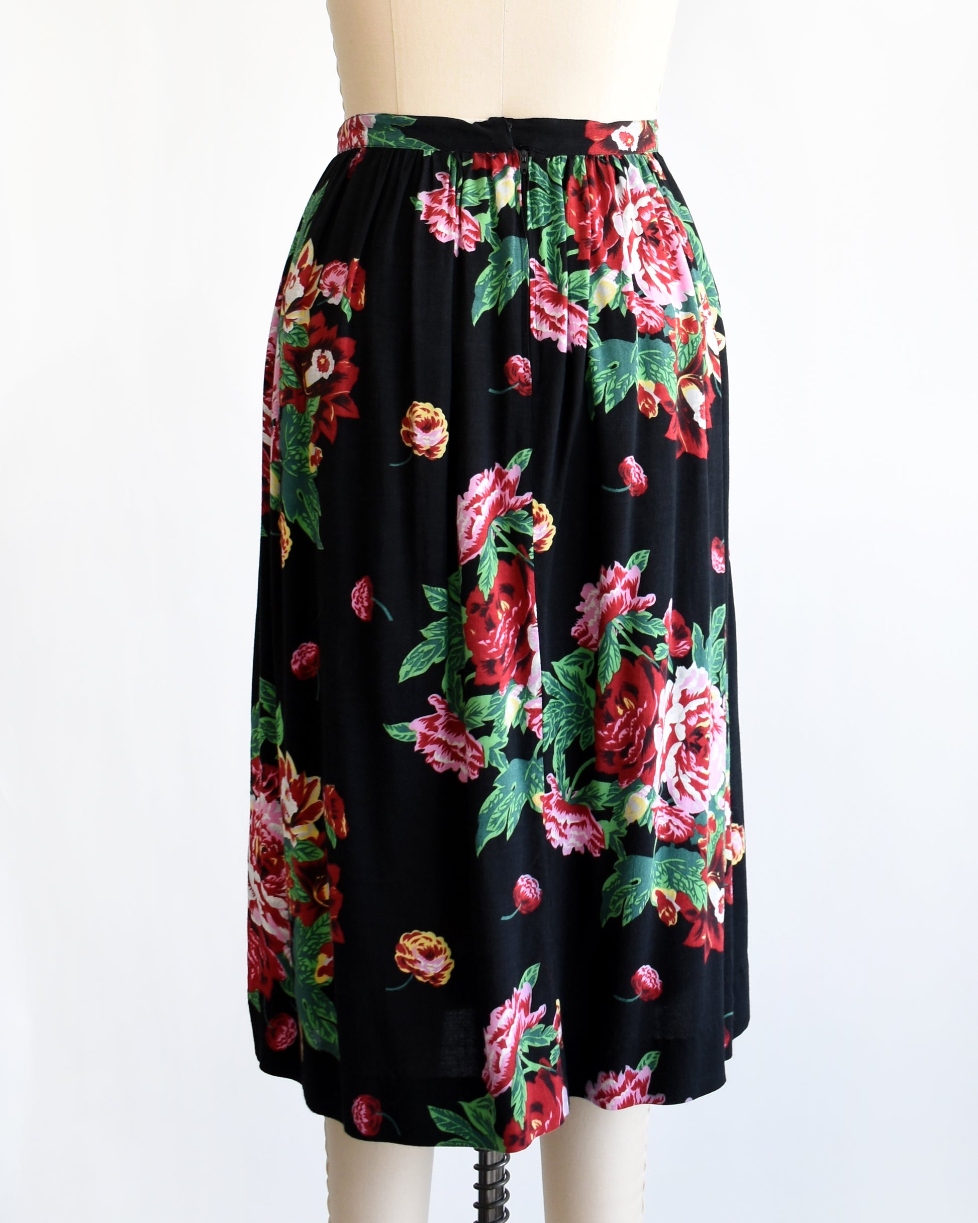 back view of a vintage 1990s black floral skirt on a mannequin against a white background