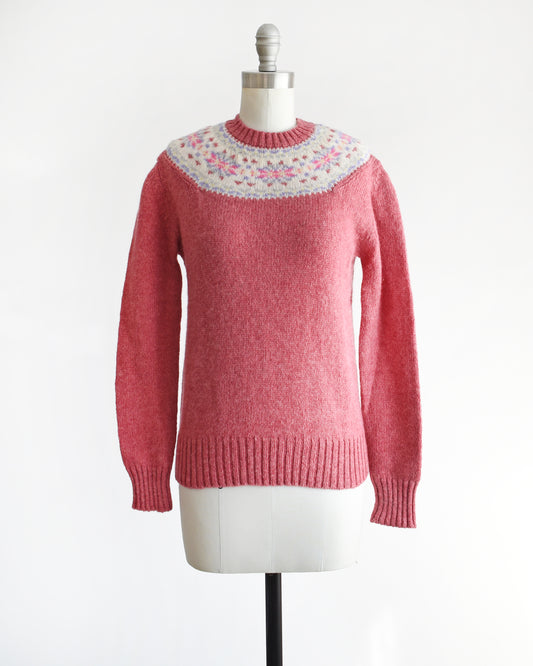 A vintage 80s raspberry pink wool sweater with snowflake motif around the collar. The sweater is modeled on a dress form.