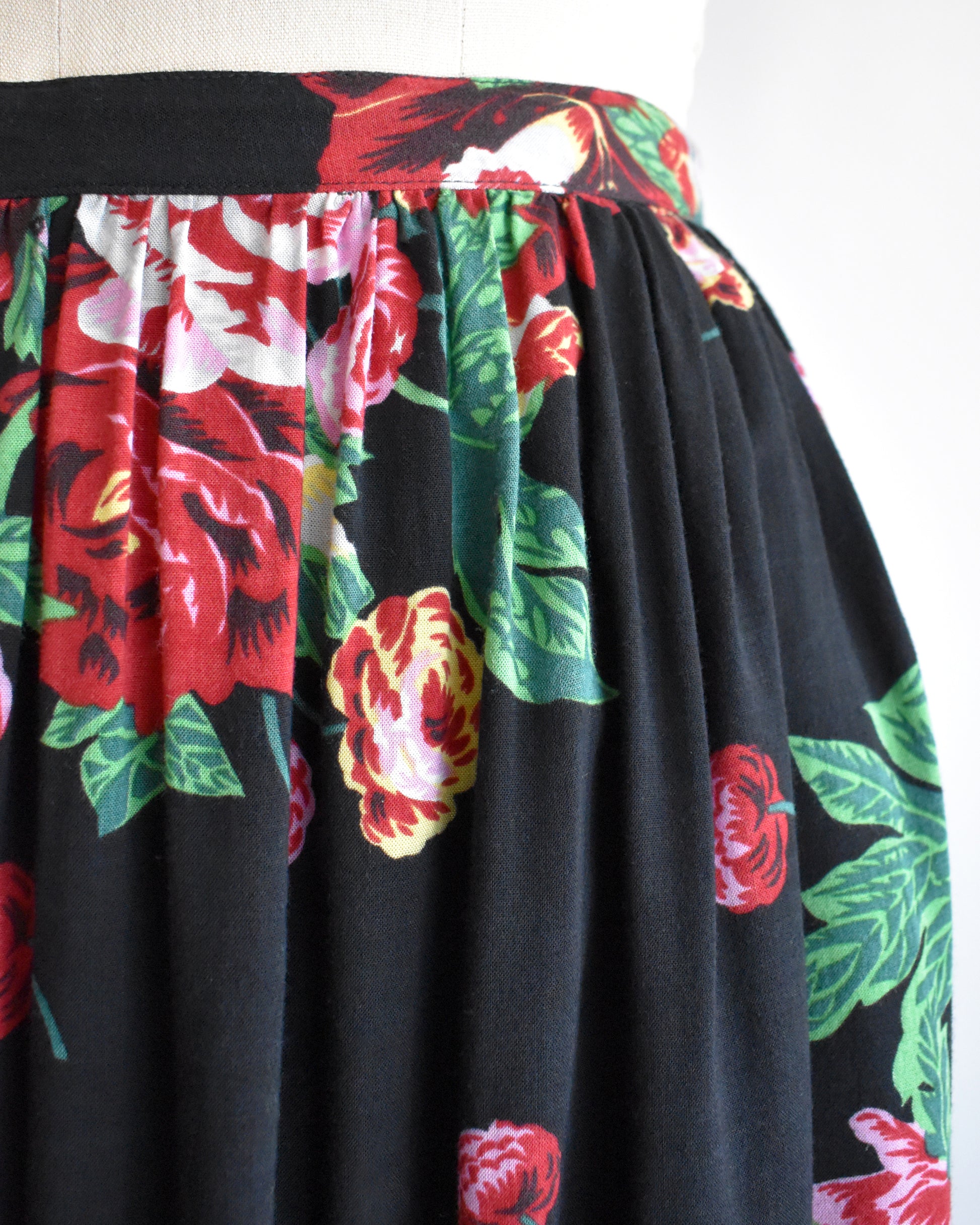 close up of the waist on a vintage 1990s black floral skirt on a mannequin against a white background