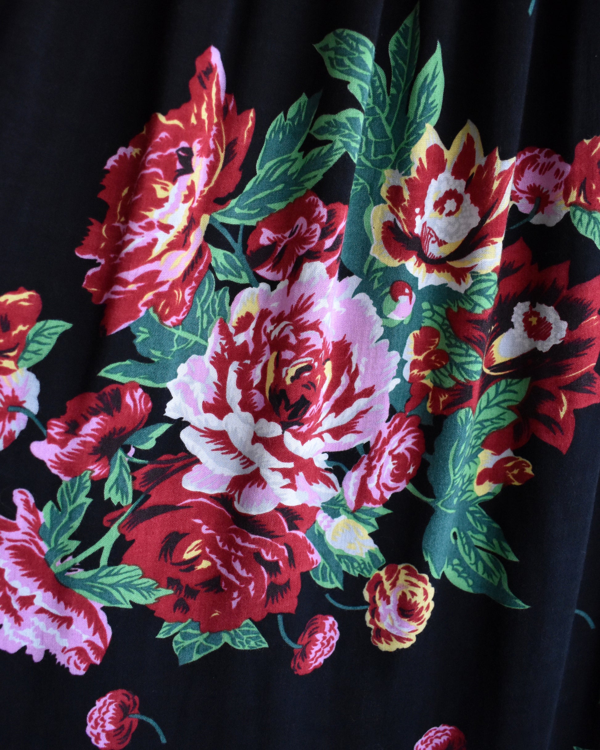 Close-up of a floral pattern with red, pink, and green flowers on a black background.