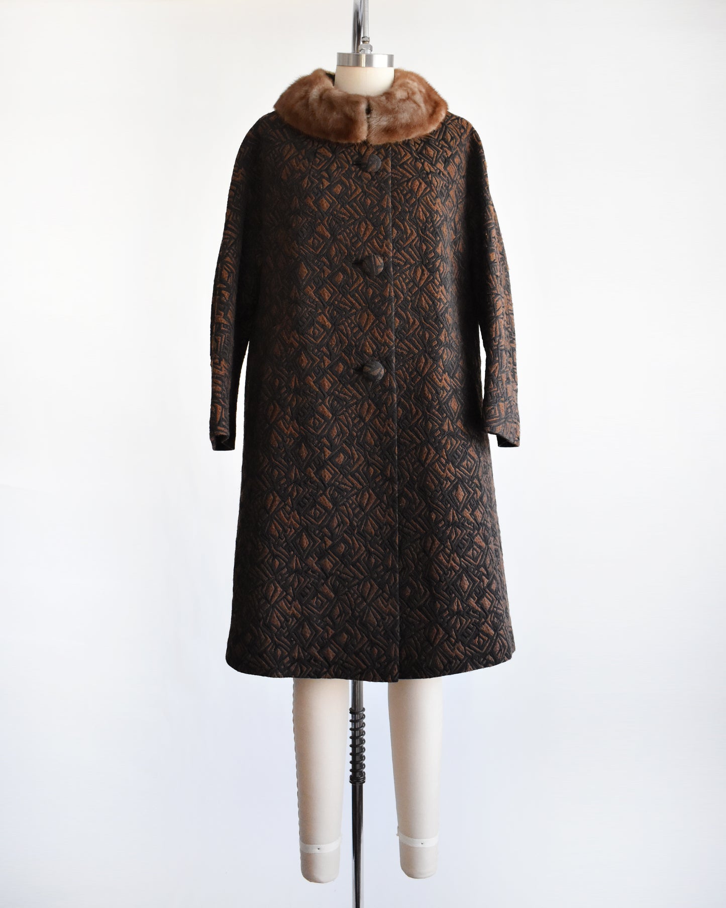 a vintage 1960s black and brown fur collar coat on a dress form against a white background