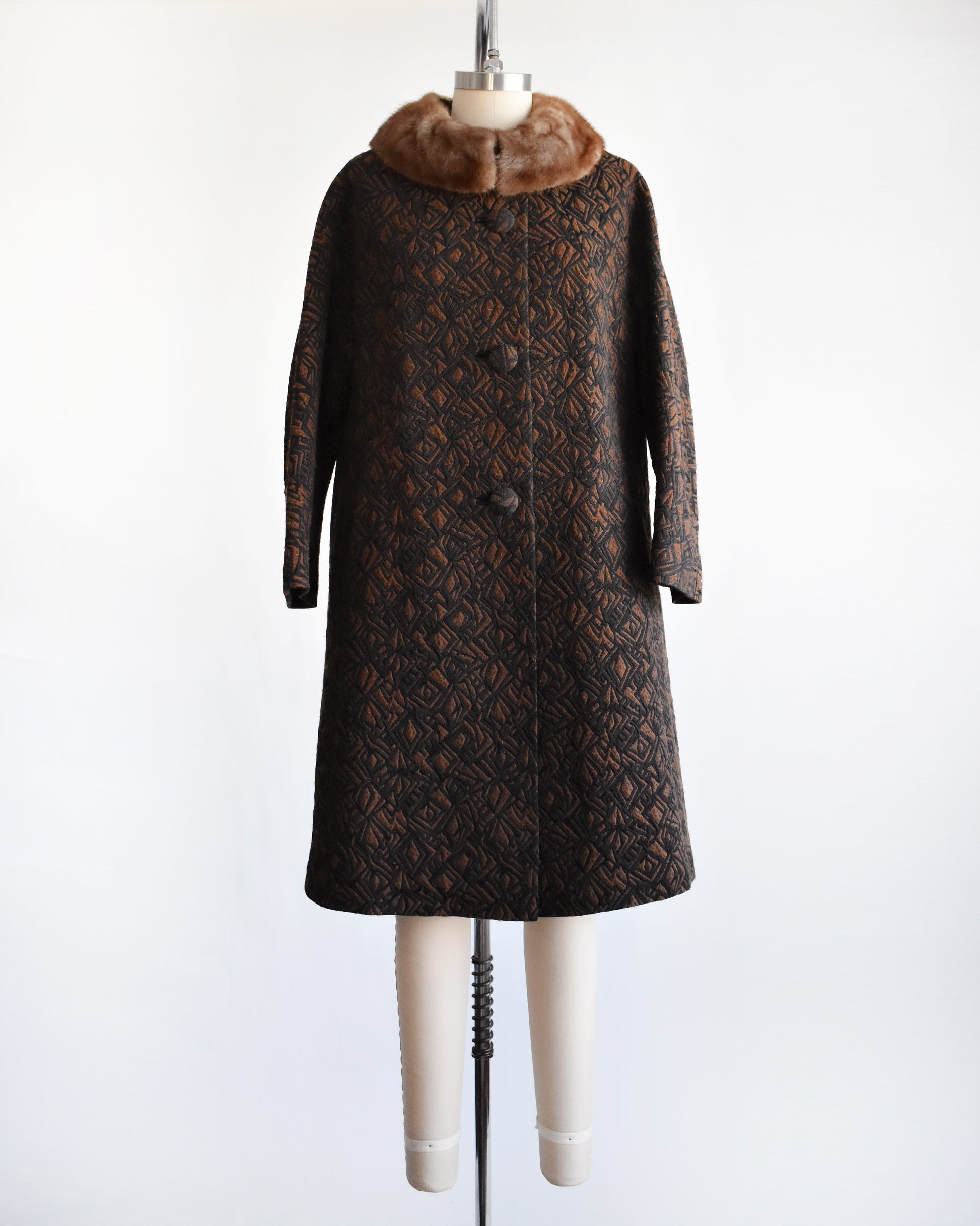 a vintage 1960s black and brown fur collar coat on a dress form against a white background