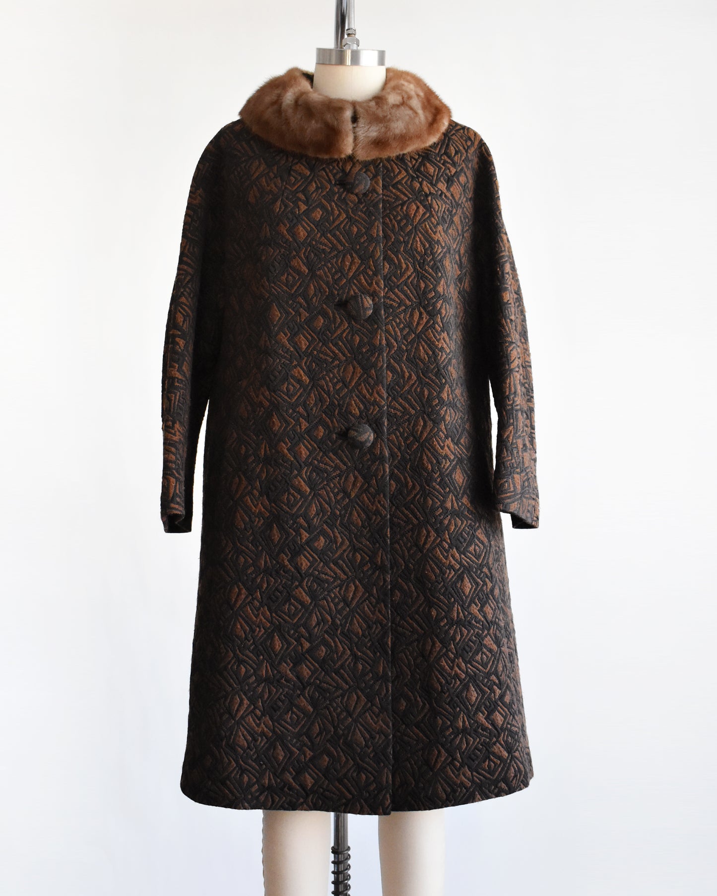 a vintage 1960s black and brown fur collar coat on a dress form against a white background