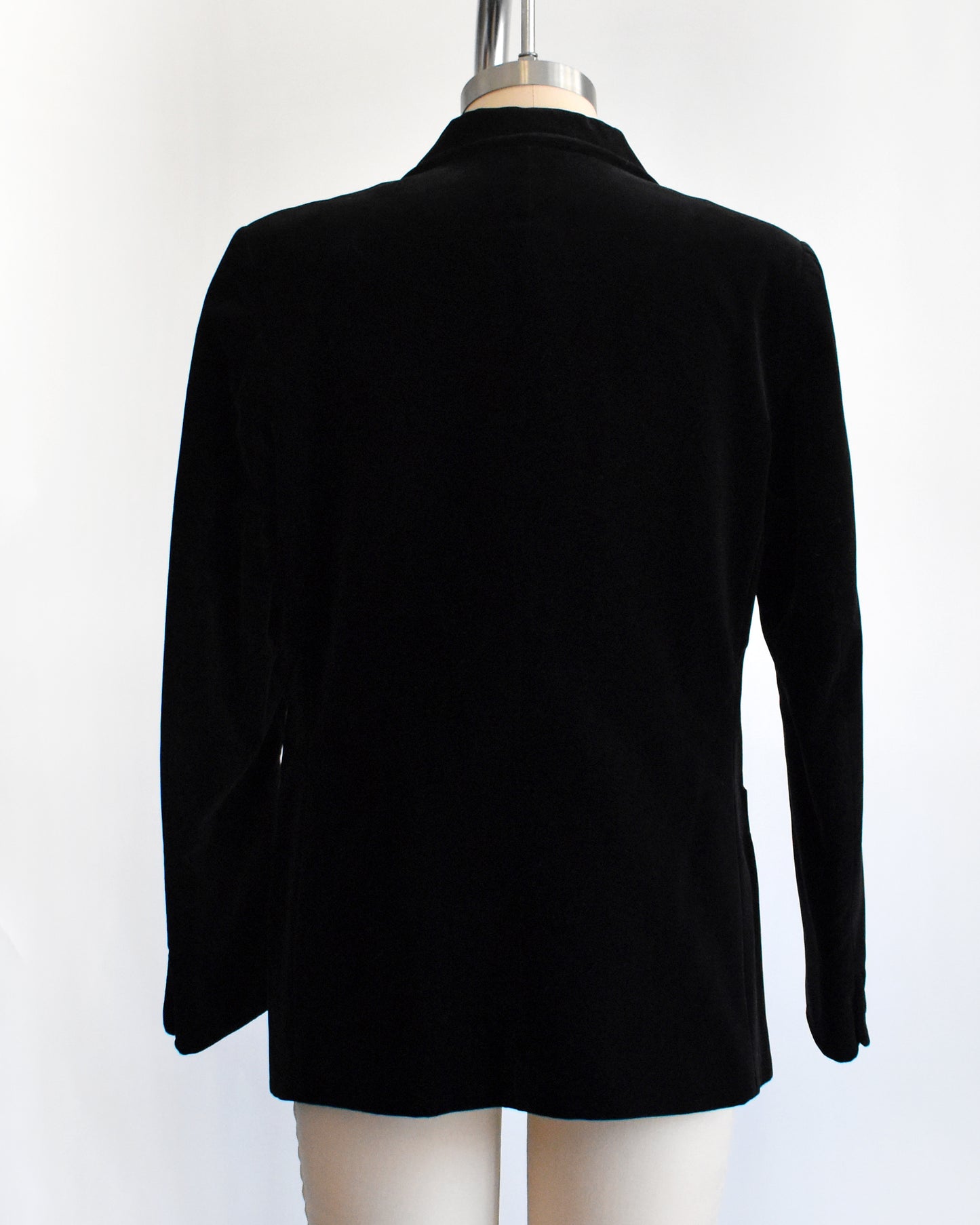 back view of a vintage black blazer on a mannequin against a white background