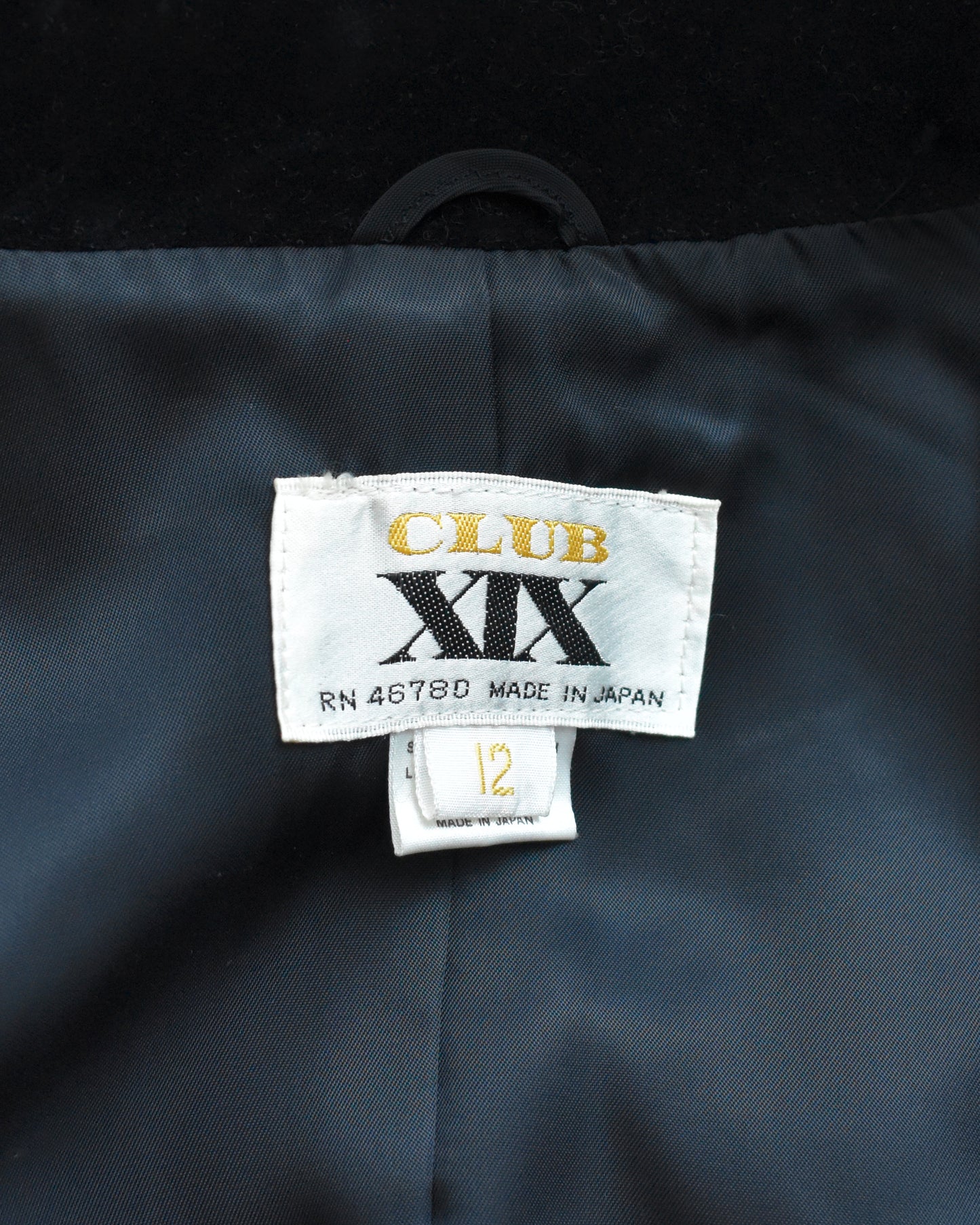 Clothing label with 'CLUB XIX' label on a dark fabric background