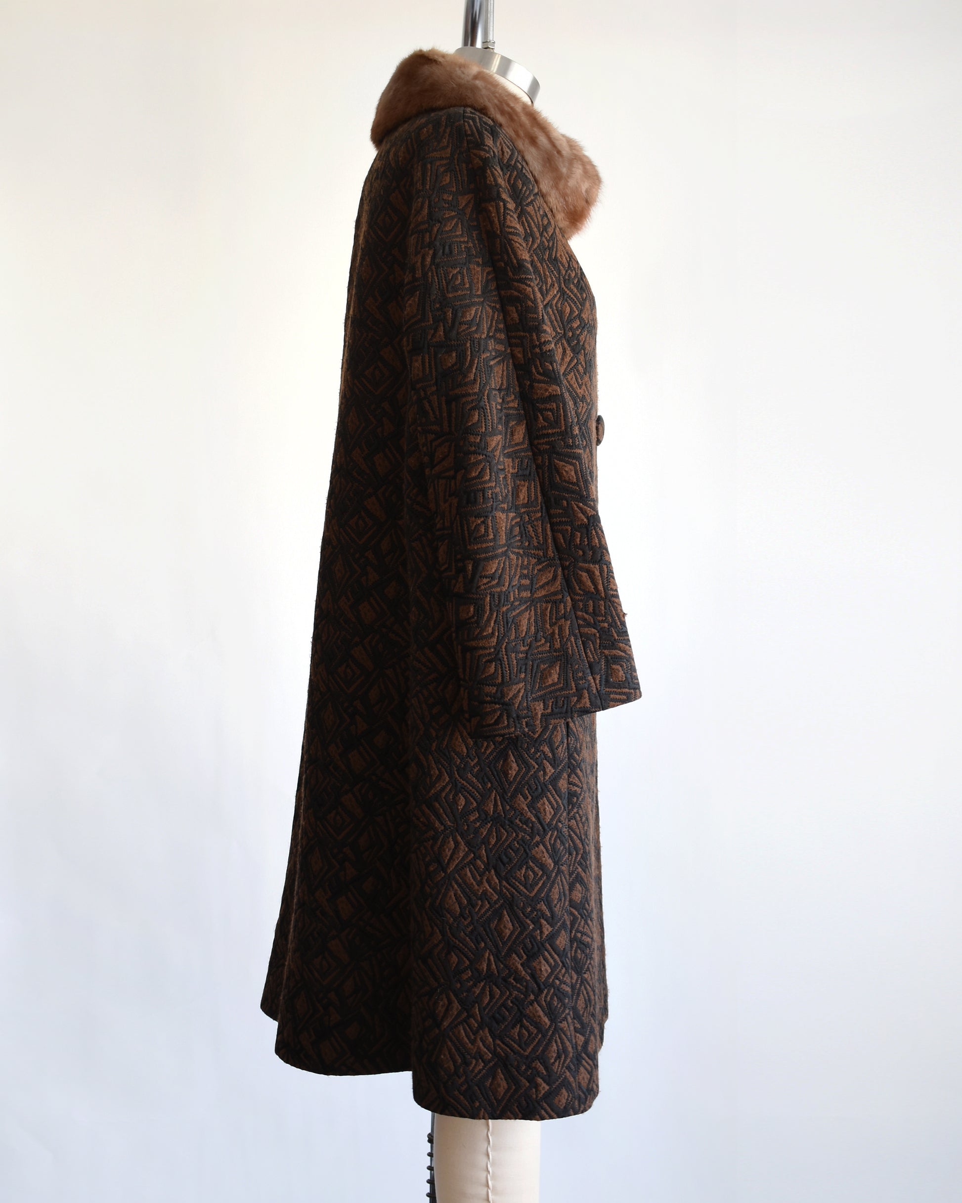 side view of a vintage 1960s black and brown fur collar coat on a dress form against a white background