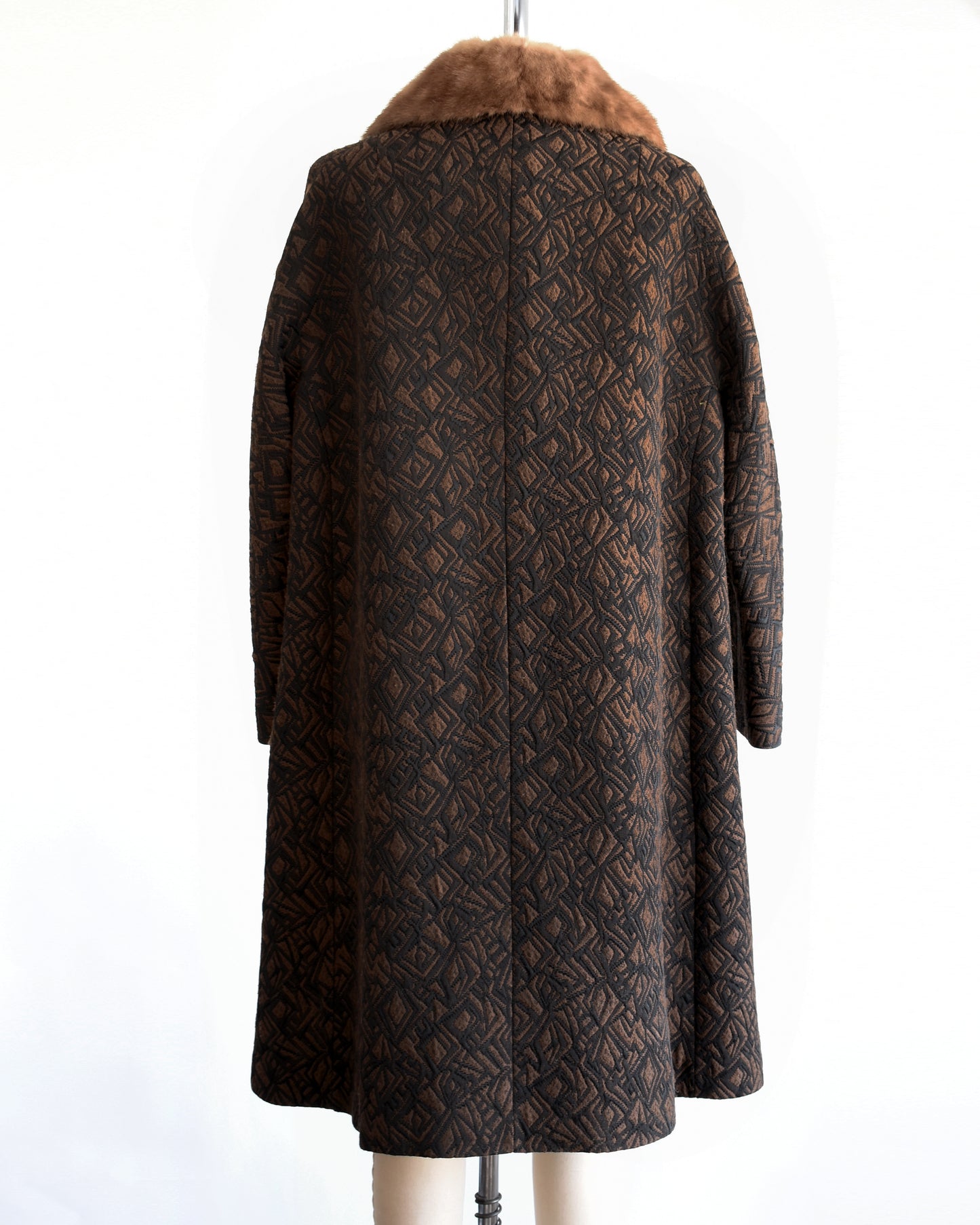 back view of a vintage 1960s black and brown fur collar coat on a dress form against a white background
