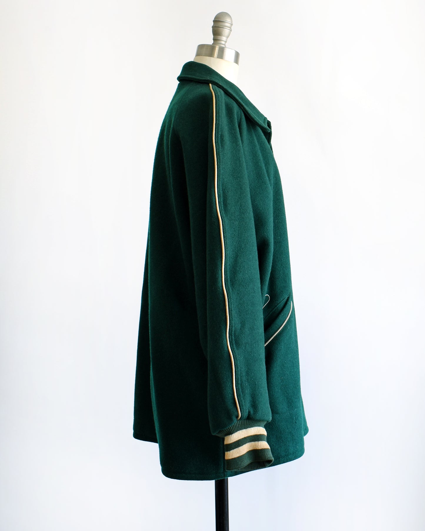 side view of a vintage 1950s green varsity jacket against a white background