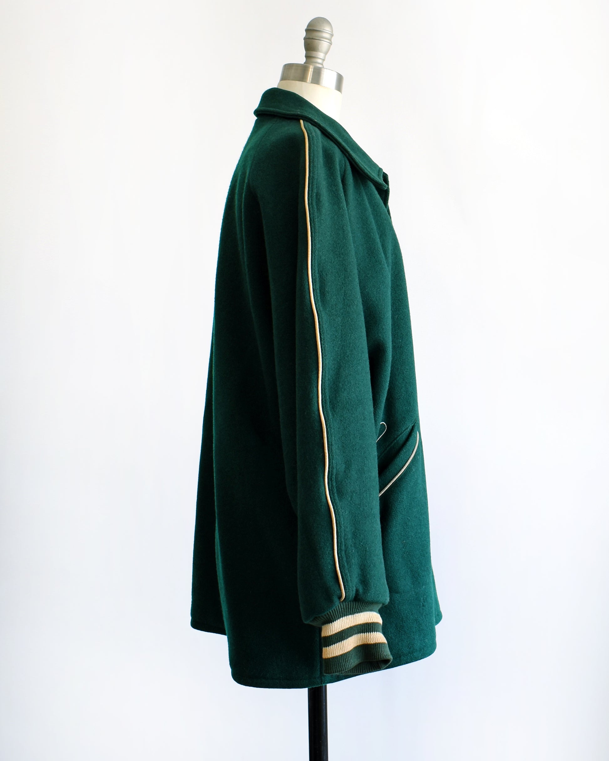 side view of a vintage 1950s green varsity jacket against a white background