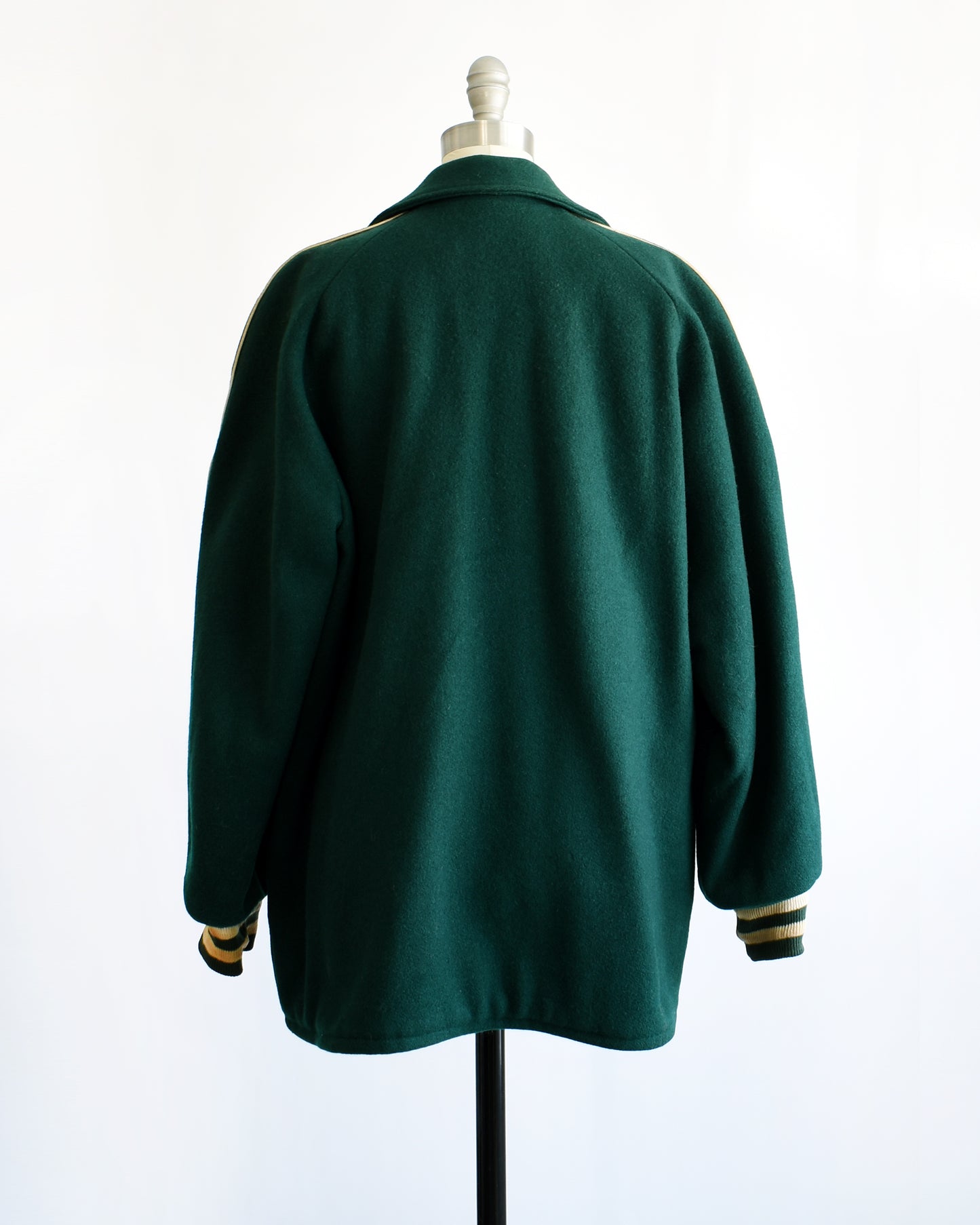 back view of a vintage 1950s green varsity jacket with white text on a mannequin against a white background