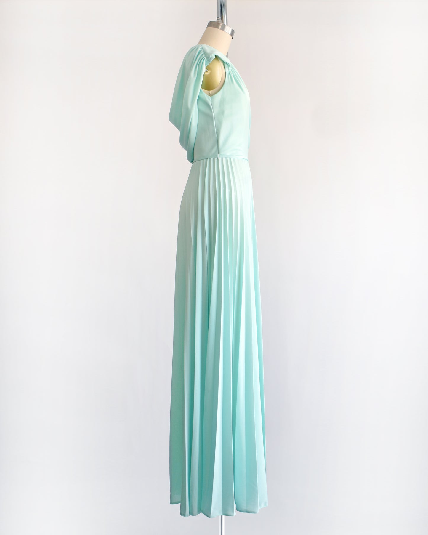side view of a vintage 1970s seafoam dress on a mannequin against a white background
