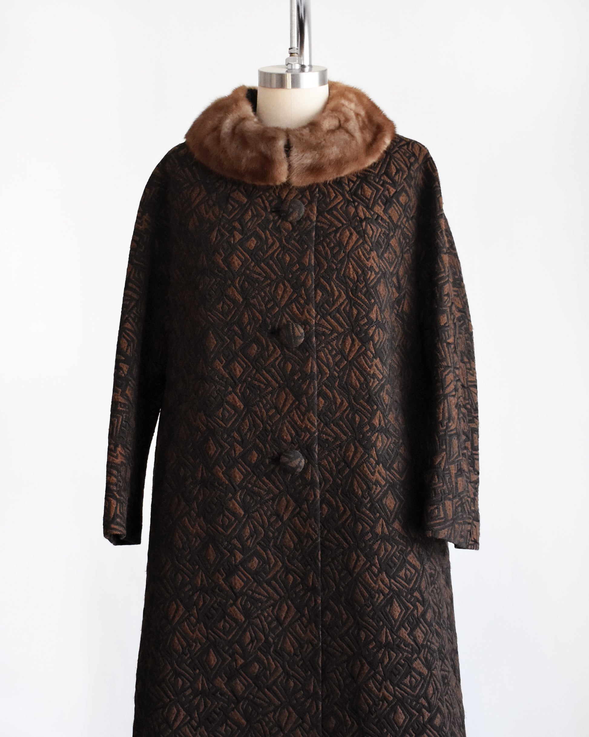 side front view of a vintage 1960s black and brown fur collar coat on a dress form against a white background