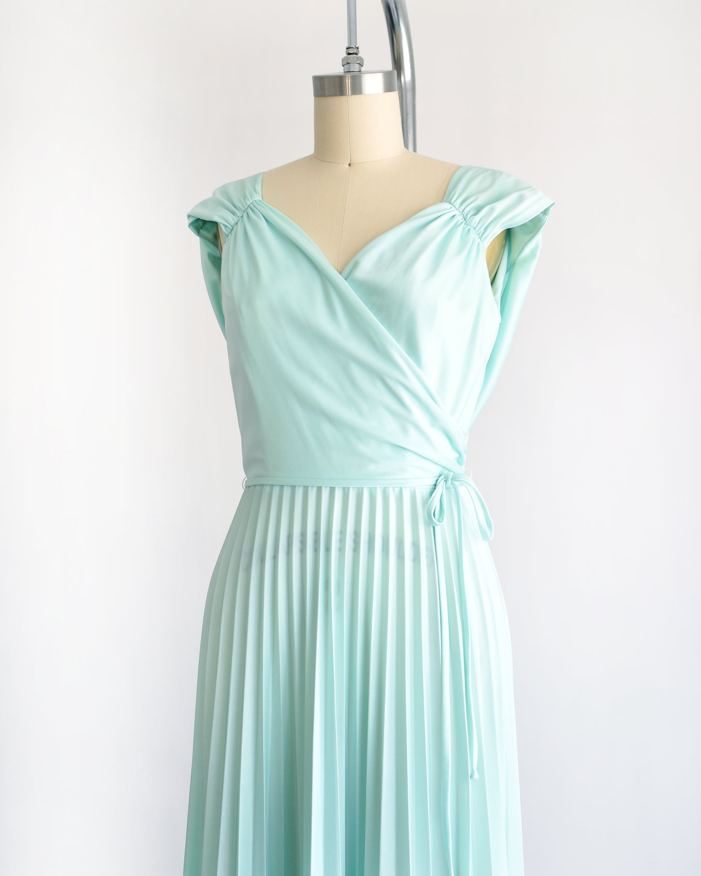 side front view of a vintage 1970s seafoam dress on a mannequin against a white background
