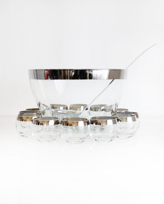 a vintage 1960s silver rim punch bowl set with ladle on a white background