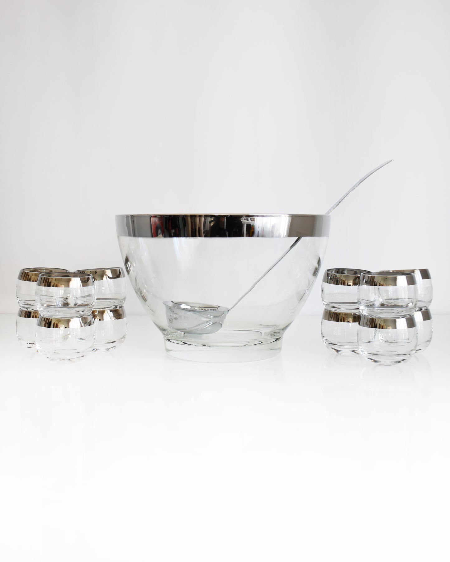 a vintage 1960s silver rim punch bowl set with ladle on a white background