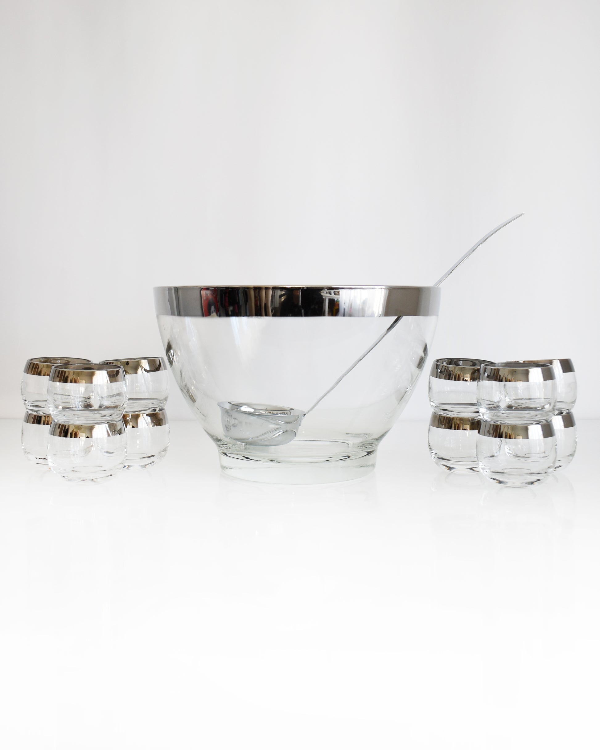 a vintage 1960s silver rim punch bowl set with ladle on a white background