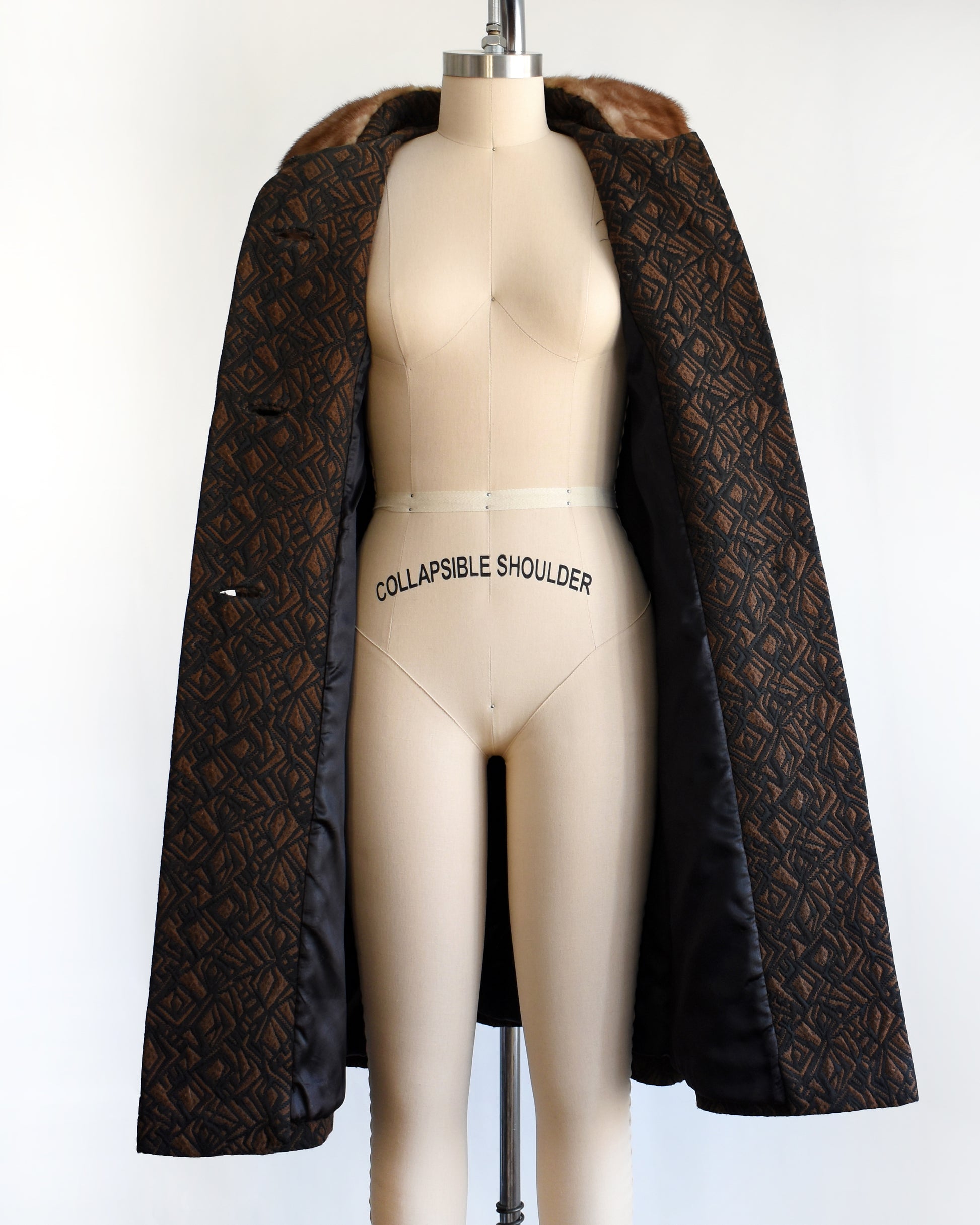 a vintage 1960s black and brown fur collar coat on a dress form against a white background. the coat is open in this photo.