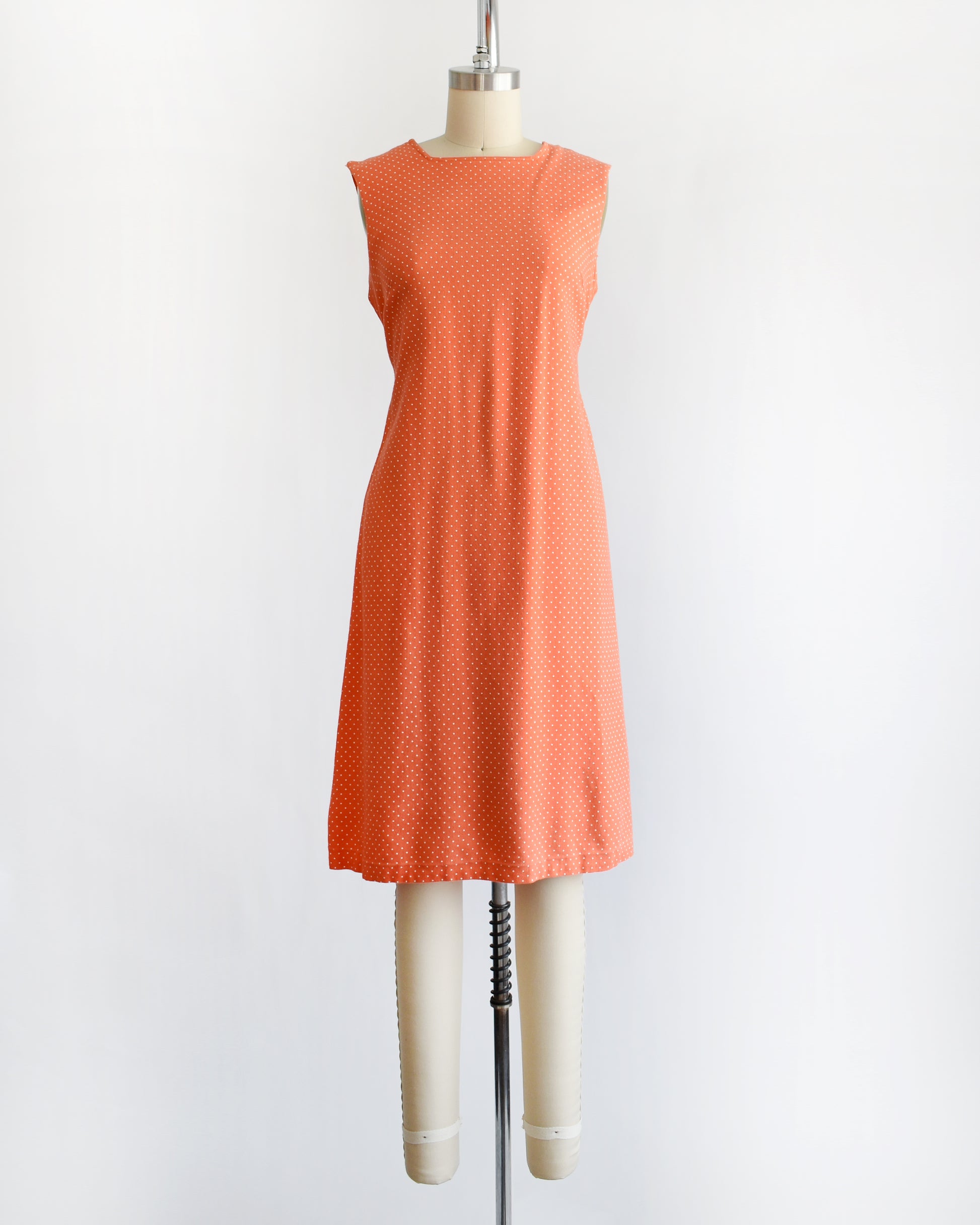 a vintage peach orange polka dot dress on a mannequin against a white background