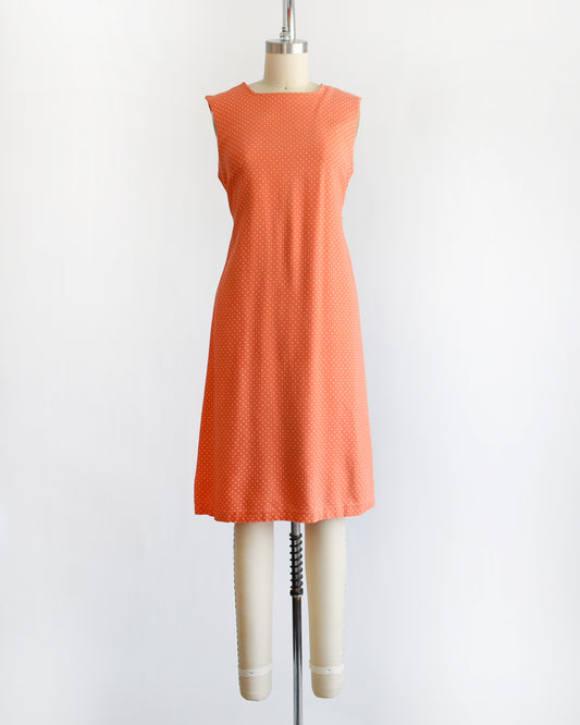 a vintage peach orange polka dot dress on a mannequin against a white background