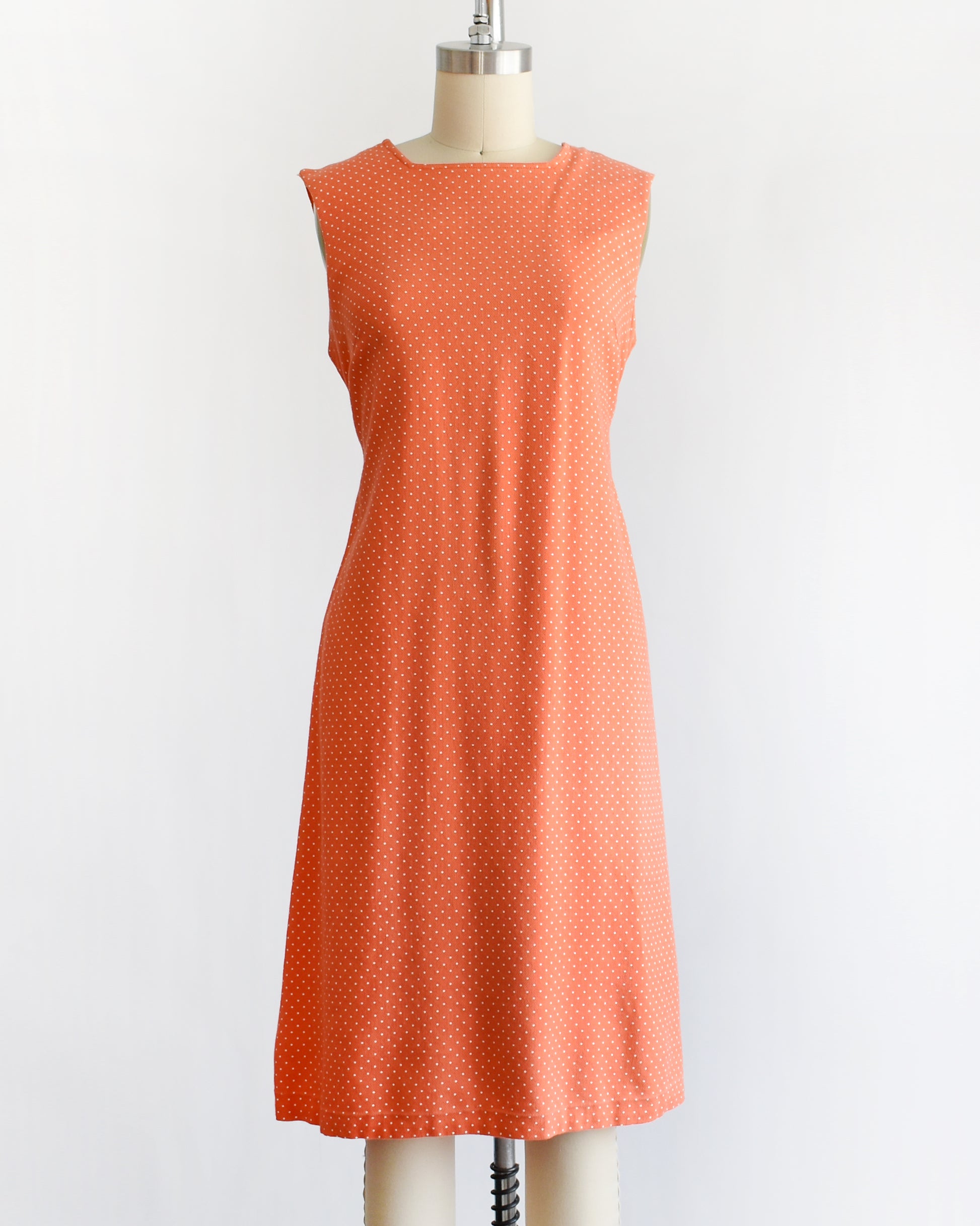 a vintage peach orange polka dot dress on a mannequin against a white background