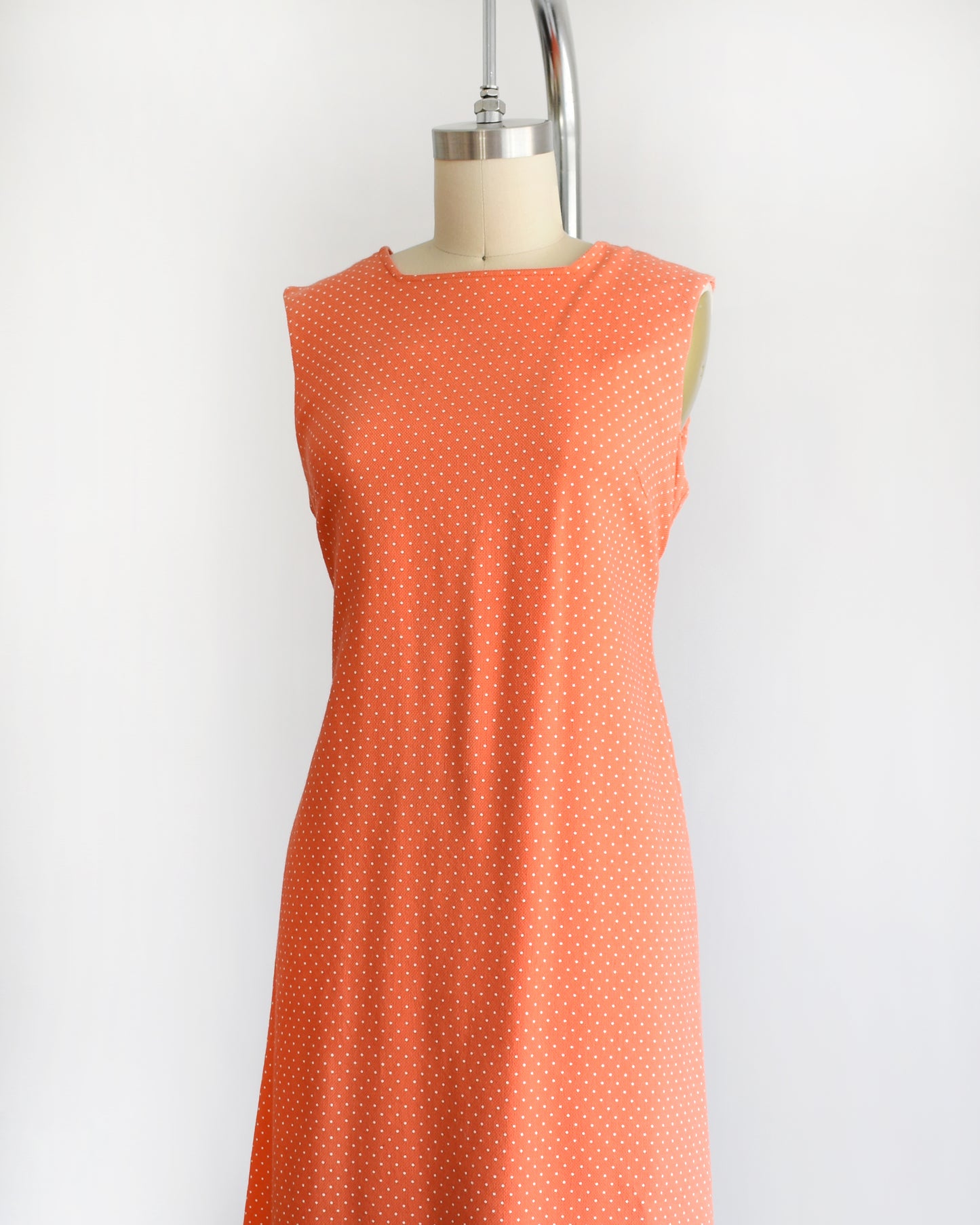 side front view of a vintage peach orange polka dot dress on a mannequin against a white background