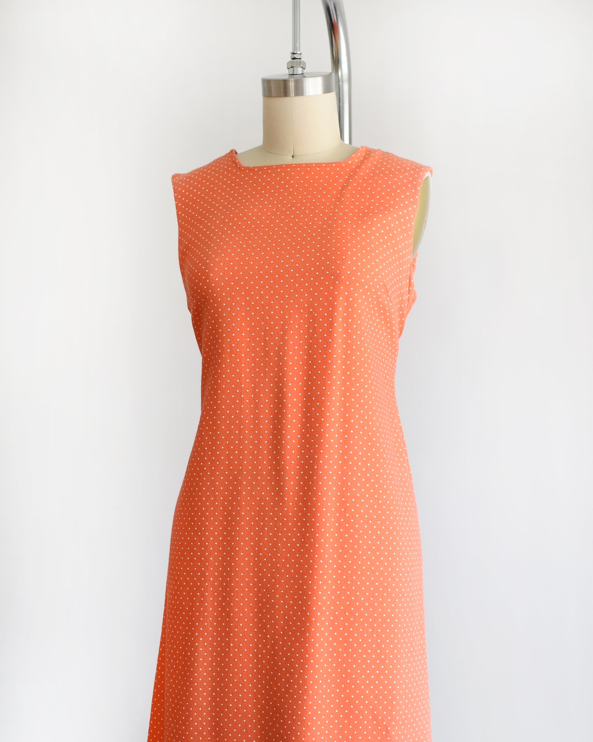 side front view of a vintage peach orange polka dot dress on a mannequin against a white background