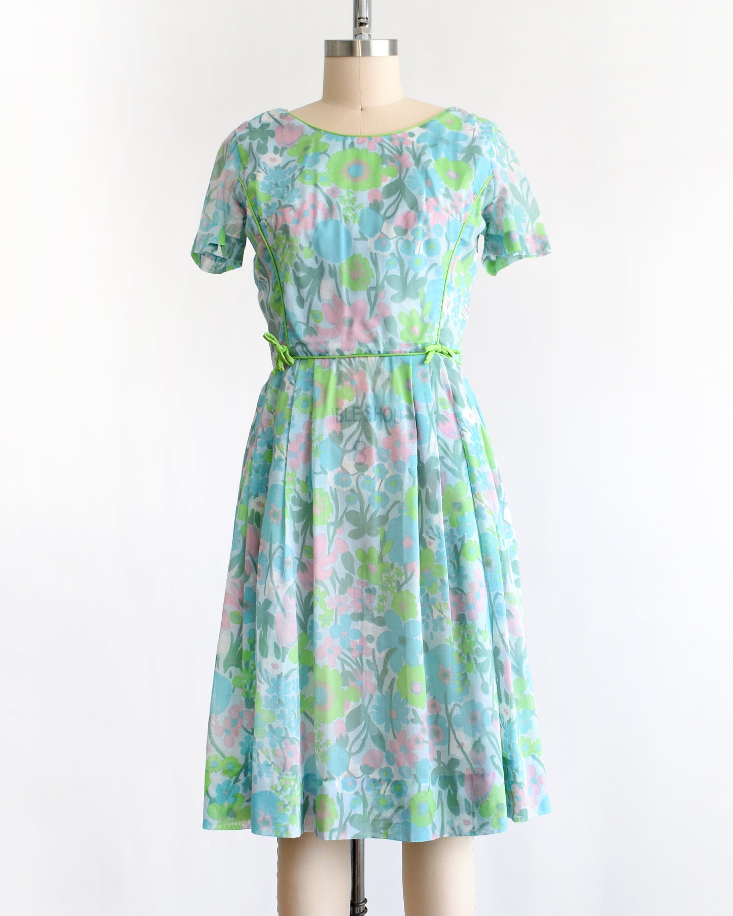 a vintage 1960s floral dress on a mannequin against a white background