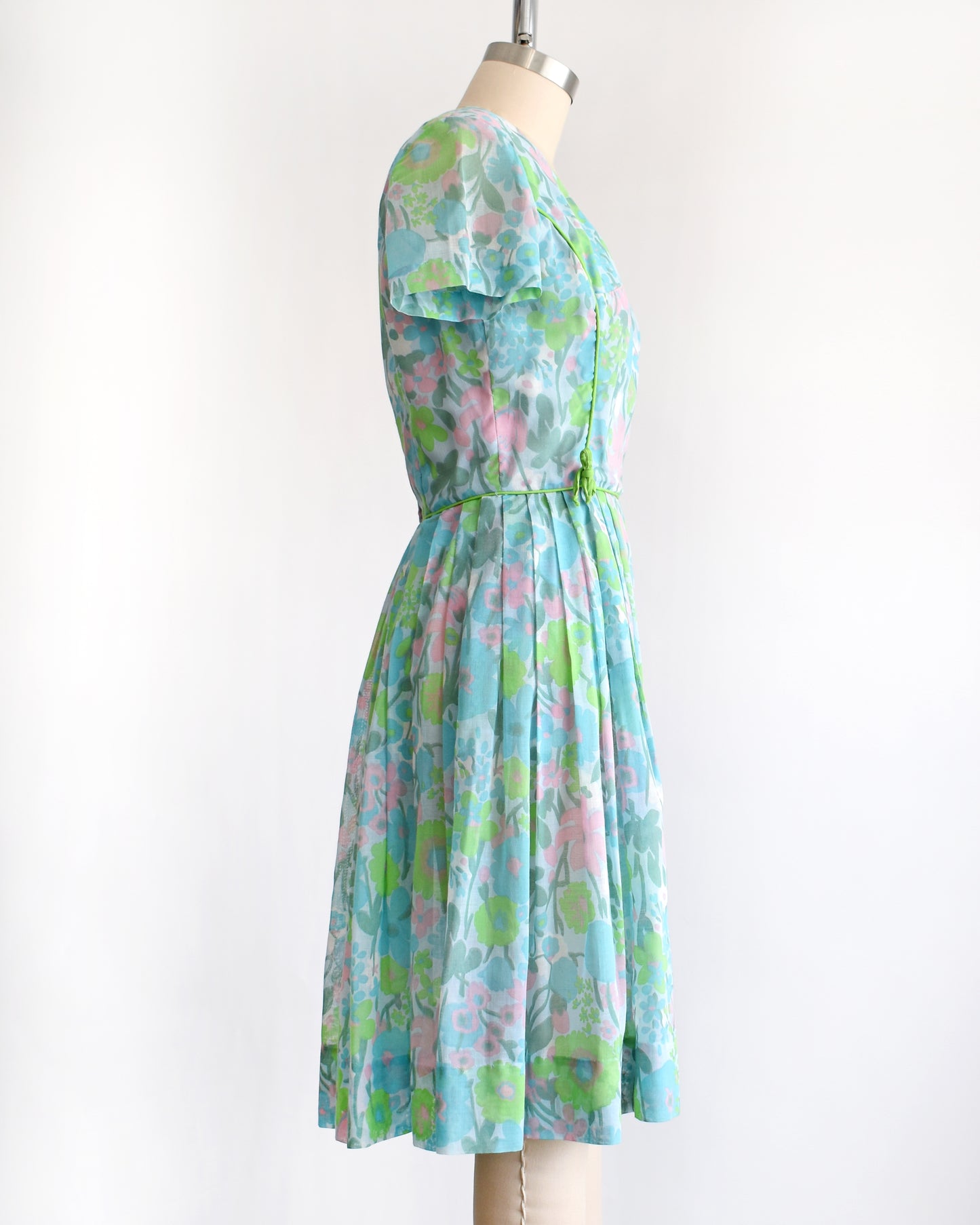 side view of a vintage 1960s floral dress on a mannequin against a white background
