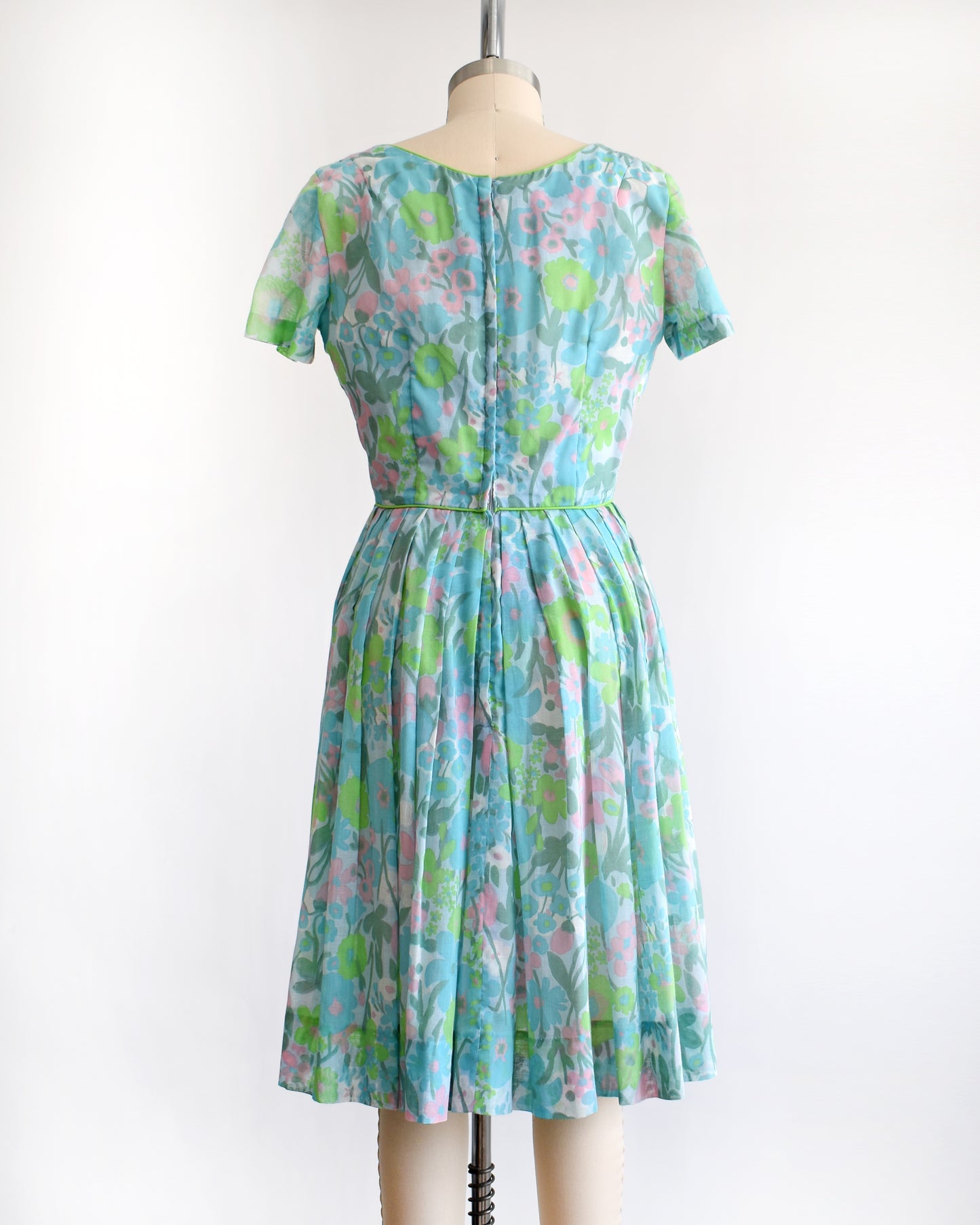 back view of a vintage 1960s floral dress on a mannequin against a white background